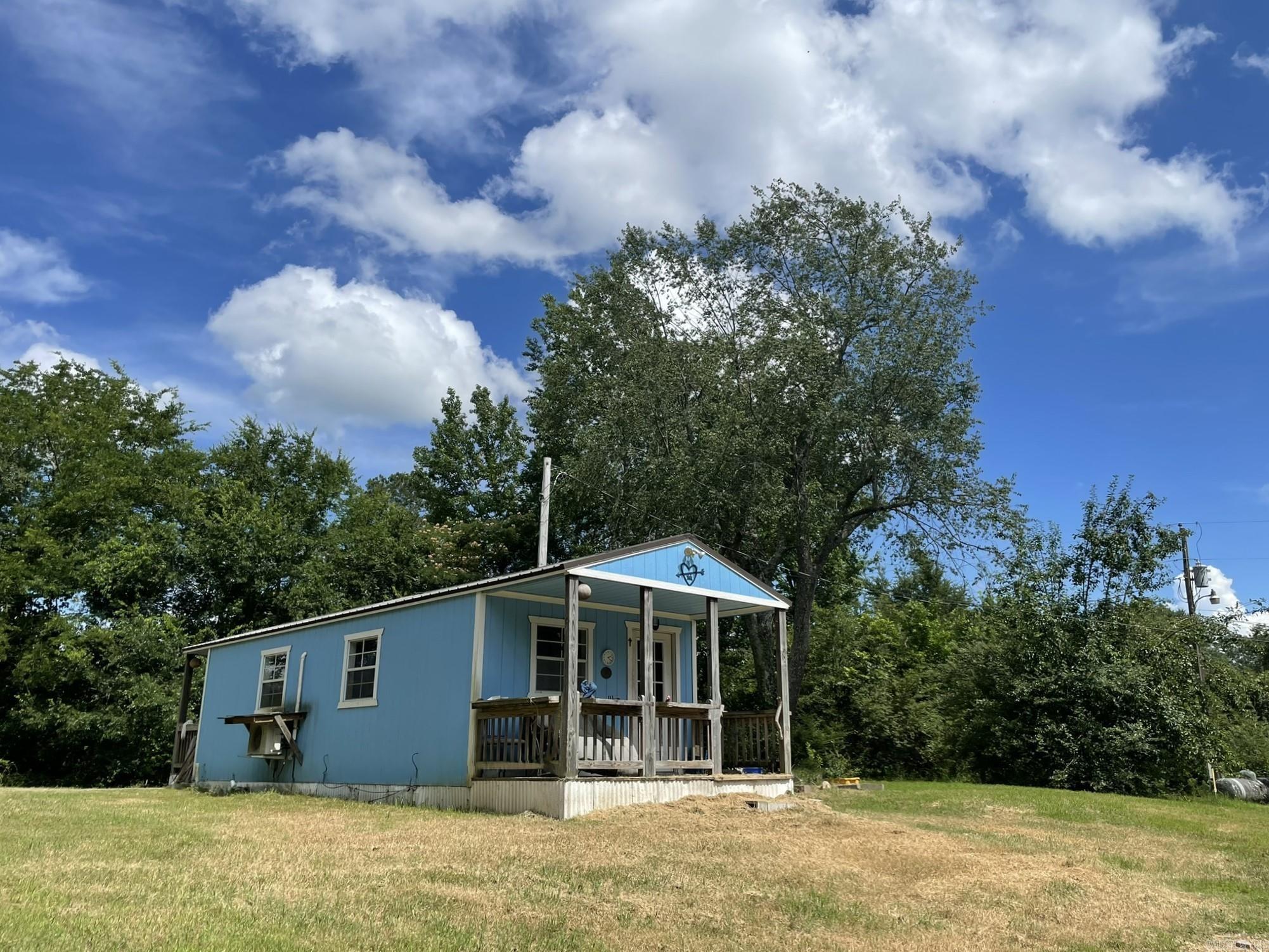 Charming furnished tiny home on a picturesque 1.09-acre lot just outside the Mena city limits! Nestled next to Grand Oak Estates. Sitting on a hill, this property features mature trees and flowering shrubs, creating a peaceful, park-like setting. Improvements include a new septic system installed in 2020 when the home was placed and a connection to city water has been added. There is a capped well on the property that could possibly be re opened. A great location with a country feel but close to town—perfect for a weekend getaway, rental, or full-time living! Not far from ATV trails, newly opened bike trails at Ward lake and under-construction lift assist bike trails to Queen Wilhelmina State Park, and all the other outdoor recreational activities the area has to offer!