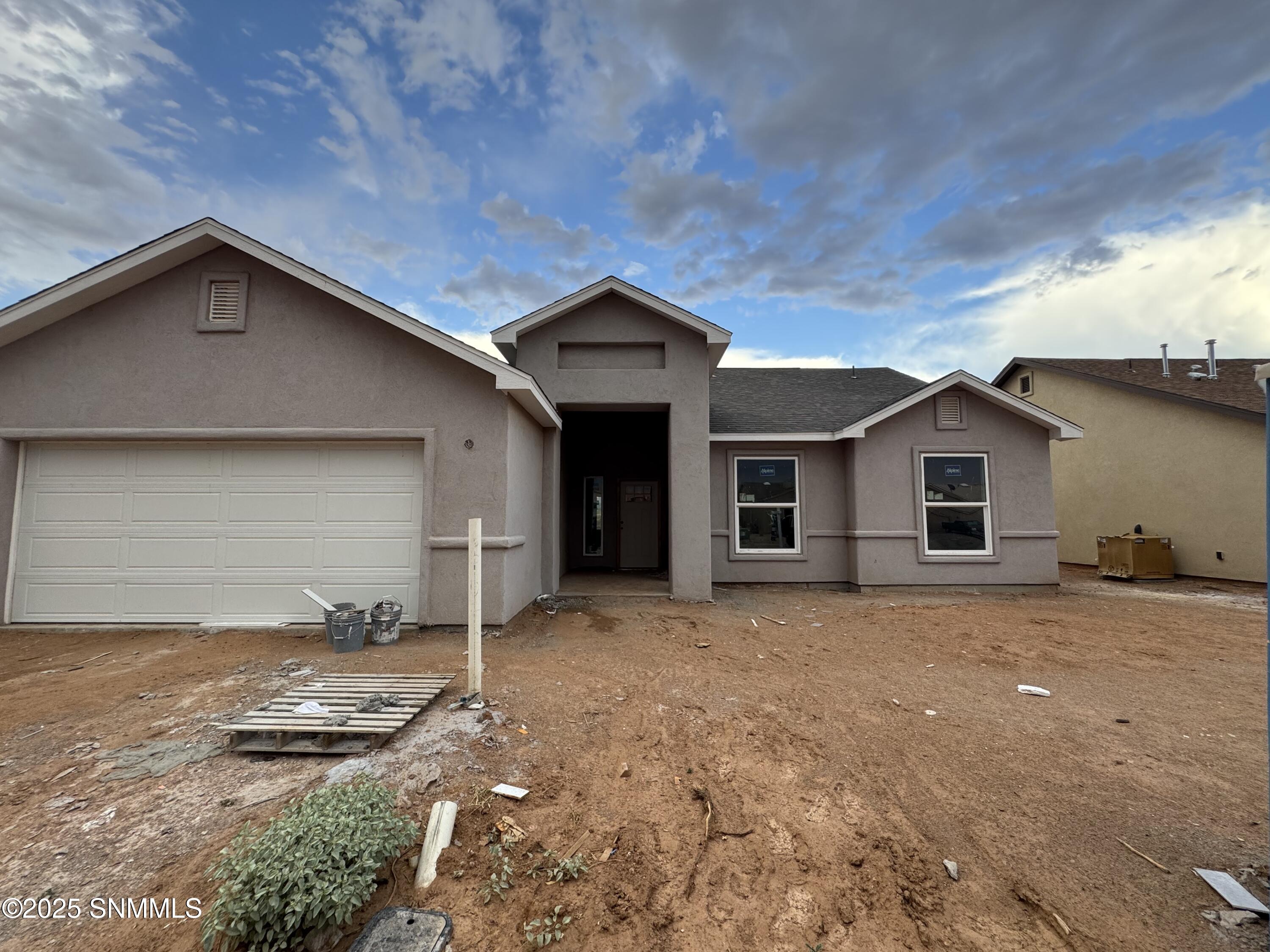 Open-concept kitchen and living room with granite countertops, stainless steel appliances, and tile flooring in a new Las Cruces NM home.