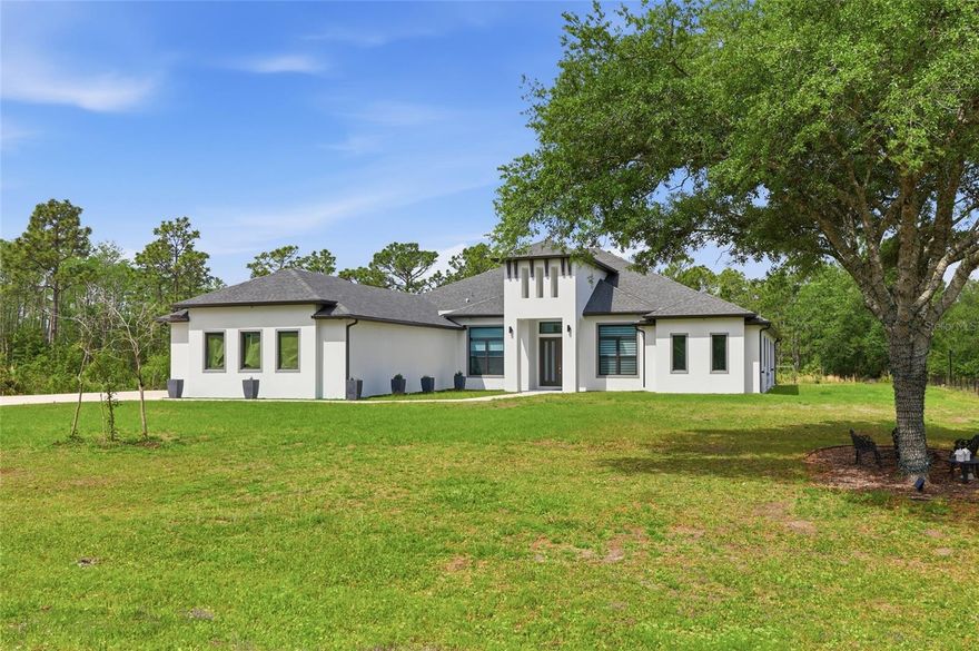Some homes check the boxes, but this one raises the bar!This custom-built luxury home in Orlando’s Wedgefield community offers 4 bedrooms, 3 bathrooms, a three-car garage, and 3,417 square feet of living space on a 1.24-acre lot. Move-in ready with a level of detail that is evident the moment you arrive.Once you step into the foyer, the home immediately makes a lasting impression. Straight ahead, the space opens into the main living area, where soaring ceilings, an open layout, and natural light fill the home. Marble-look porcelain tile runs throughout, while a custom painted acrylic accent wall anchors the living room as a striking focal point. Coffered ceilings, crown molding, and statement chandeliers bring a polished, elevated finish.To the right of the foyer, a private office with French doors offers a quiet, well-placed space to work or focus. Also on this side of the home, the primary suite is set apart, designed with handicap accessibility and delivering every indulgence, including a freestanding soaking tub, a glass-enclosed walk-in shower, dual vanities, a private water closet, and a room-sized walk-in closet that serves as its own private dressing room. Moving into the main living area, the kitchen and living spaces connect with ease. The kitchen features quartz countertops, soft close solid wood 42 inch cabinetry, a large island with seating and plenty of storage, along with a walk-in pantry. The laundry room is conveniently located nearby, complete with cabinetry, shelving, and a sink. The dining area sits just beyond, well positioned for both everyday meals and entertaining. From the living room, oversized multi-panel sliding glass doors open to a covered back porch, extending the living space outdoors. The porch offers plenty of room for a future outdoor kitchen, gatherings, or a screened-in retreat. To the left side of the home, the guest wing is thoughtfully laid out. Two bedrooms share a Jack and Jill bath, while the third bedroom is positioned near a separate guest bath, with the hallway providing direct access to the back porch. The property has been leveled with fill dirt and is ready for what comes next. Whether you envision an accessory dwelling unit, additional parking, or future expansion, the groundwork is already in place, including a dedicated electrical panel ready for future connection. Added insulation over the garage and porch helps keep the home comfortable and energy efficient year round, and a whole house filtration system is in place. This home has an unbeatable location in the highly sought-after Wedgefield community, offering easy access to SR 528, 417, Orlando International Airport, and top-rated schools. Schedule your private tour today because this is the one!