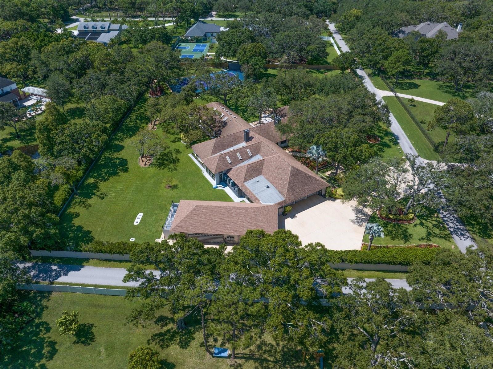 Prepare to be amazed by this extraordinary estate home tucked within Kent Place—one of Clearwater’s most coveted and private neighborhoods, where country-style living meets city convenience. Designed with vision and created with care, this home is a true masterpiece, ideal for car collectors, art lovers, or multigenerational living. Pride of ownership is evident from the moment you arrive, with impeccable landscaping, majestic oaks, and a stately executive presence. Step inside to a gallery-style foyer that sets the tone for the home's artistry and attention to detail. Just beyond, the Key West-inspired room transports you to the southernmost point of Florida with hand-painted murals, skylights, and a wall of floor-to-ceiling windows—a serene escape unlike any other. Entertain in style with a full wet bar leading to a cozy family room with fireplace and cigar cabinet and wine cellar, open to a chef’s kitchen featuring top-of-the-line stainless steel appliances, a center island with vent hood, and access to one of the home's showstoppers: an enclosed indoor pool and spa surrounded by custom murals of Tampa Bay's iconic landmarks. A commercial Wolf grill ensures unforgettable gatherings. The pool can be closed off and separated by glass, accordion sliders. The formal living and dining rooms are a work of art themselves, featuring custom wall murals and grand spaces perfect for hosting intimate dinners or entertaining on a grand scale. The primary suite is a world of its own, complete with a private office featuring a poured concrete safe, a second laundry, a sitting room with custom built-ins, a spa-like ensuite with jetted tub, walk-in shower, double vanities, and an unforgettable custom closet with lighted glass cabinetry, endless storage, and a substantial staircase leading to a cedar-lined closet. Guests will marvel at the castle-like guest suite with soaring ceilings, a whirlpool tub, walk-in shower, steam room, and sauna. Two additional bedrooms with walk-in closets and natural light share a Jack-and-Jill bath. An attached two-bedroom, two-bath apartment with full kitchen and theater room offers the perfect solution for a nanny, in-laws, or long-term guests. For the car enthusiast, a 6 bay garage with four car lifts allows for storing 10-cars. A dream come true, while a separate 3-car garage provides additional storage and access to a large laundry room. Hurricane impact windows with shutters, two home generators that will power a significant portion of the home, storage galore, and custom features around every corner make this a once-in-a-lifetime opportunity to own a truly remarkable Clearwater estate. Ideally located close to shopping, dining, two airports and pristine beaches .Don't miss your chance—homes like this are rare and unforgettable!