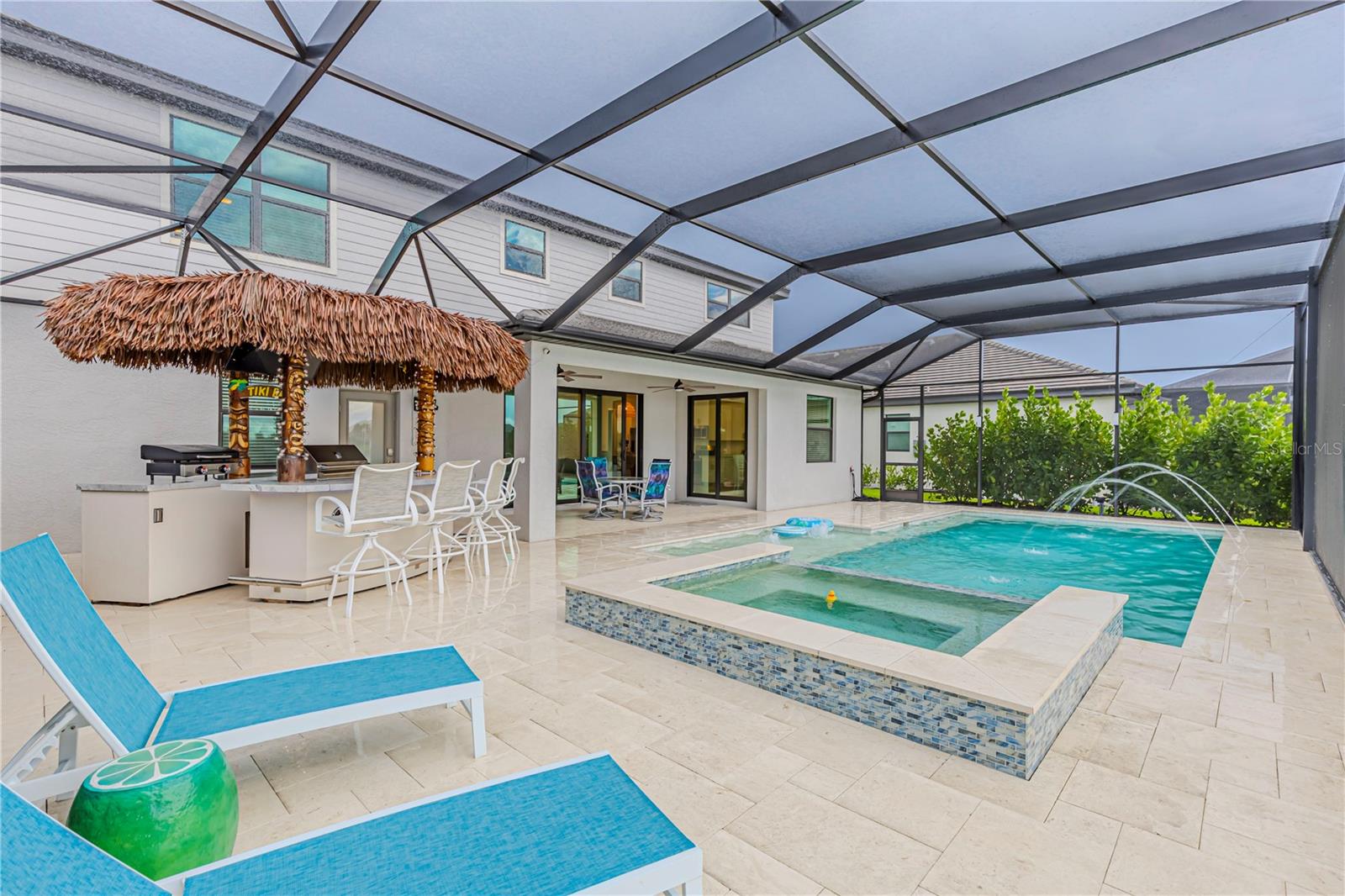 This family home combines luxury, privacy, and resort-style amenities, thoughtfully designed for both relaxation and entertaining. Step outside to your private backyard paradise, where a 400,000 BTU gas-heated saltwater pool and spa await. The pool area showcases travertine pavers, water features, a cascading spa waterfall, and a sun shelf with bubblers. Two separate pumps keep the pool, spa, and water features running at their best. A tiki hut outdoor kitchen creates the ultimate entertaining space with two refrigerators, two warmers, a gas grill, Blackstone, full stereo system with LED lights, TV, and a ceiling fan. The panoramic lanai screen with extended height provides unobstructed southeastern lake views, while ceiling fans throughout the lanai keep the air flowing. The spa offers wrap-around seating, making it the perfect retreat after a long day. With 455 square feet of pool area and nearly 1,000 square feet of outdoor living space, this home is a true showcase of the Florida lifestyle. Inside, thoughtful upgrades can be found throughout. The pool bath features upgraded shower glass, and all bathrooms include built-in shower shelves. Lighting and fan upgrades include a dramatic two-story ceiling fan, and the garage is finished with epoxy flooring, LED lighting, and hurricane impact protection. A gas stove and gas water heater add efficiency and convenience. Situated on a 62-foot lot, this property offers privacy with six-foot clusia hedges on both sides and peaceful southeastern lake views. Living in Verdana Village means enjoying unmatched community amenities. The main amenity center offers a restaurant and bar, indoor and outdoor pickleball and tennis courts, a full indoor basketball court, fitness center, dog park, playground and a resort-style pool and spa. Homeowners in this neighborhood also have access to the brand-new West Amenity Center, exclusive to West Village residents. This satellite center includes a fitness center, pool, lap pool, and spa. With low HOA fees that include landscape maintenance, this home delivers both luxury and value. This five-bedroom, four-and-a-half-bath, three-car garage Lennar Sorrento is more than just a home—it’s a complete lifestyle.