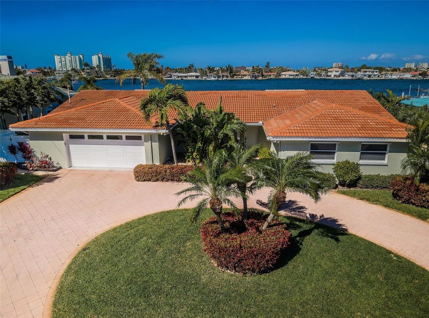 AN EXCEPTIONAL 4 BEDROOM 3 ½ BATH WATERFRONT RESIDENCE LOCATED ON BEAUTIFUL DEEP WATER IN ST. PETE BEACH’S PREMIER WATERFRONT COMMUNITY.HEART OF ST. PETE BEACH! Beautifully and impeccably landscaped with a fine brick paver circular drive and an appealing private 22ft-wide courtyard entry, you’ll love the spacious open floor plan design of this wonderful home. Beyond the lovely foyer entry, you’ll be drawn to the fine dining area overlooking the courtyard and the expansive great room with dazzling views of the waterfront. Overlooking the waterfront and opening to the pool deck, the resplendent designer kitchen boasts rich granite counters, coastal white cabinetry, gas cooking, extensive storage, under-cabinet lighting  and two Bosch dishwashers. The Wine Chiller does not convey. The exceptional owner’s suite provides stunning water vistas and opens to the covered pool deck. The suite features two separate closets, including a huge walk-in closet. Owner’s bath is an indulging retreat, with a posh soaking tub, walk-in glass rainshower enclosure with body wand, dual vanities with lavish quartz counters and inspiring minimalistic cabinetry. Bedroom 2 is private and oversized and bedrooms 3 and 4 are suitable for numerous purposes – including bedrooms, offices dens. The exquisite full guest bath offers dual quartz vanities, and a multi-head show/tub. The fine full pool bath sits adjacent to the indoor laundry and provides access outside the home. Step out to the backyard oasis and take in dramatic open water views that extend approx. 800ft across. A fine brick paver deck encircles the sizable swimming pool. You’ll love the 265 sqft covered lounging/outdoor dining area overlooking the waterfront – perfect for entertaining friends and family. The boat dock and lift rest on deep sailboat quality water. From your dock to the Gulf of Mexico in just 15 minutes. Numerous value-added updates include 24KW gas generator, gorgeous driftwood style flooring, elegant window treatments, hurricane storm window protection and much more. Experience amazing water views by day and brilliant sunsets at night. A truly uncommon location where all homes are on the water! A fantastic value within 10-minute walking distance of dining, shopping, entertainment, and the pristine soft white sands of Trip Advisors #1 rate beach. All dimensions are estimates, buyer to verify.