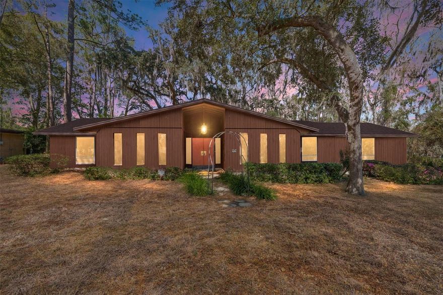 3-bedroom, 2-bath home in the Ridgewood neighborhood offering 2,172 heated and cooled square feet and 2,894 total square feet including an oversized two-car garage. Double-door entry opens to a foyer with terrazzo-look flooring. The home features a separate living room, formal dining room, and family room. The family room includes a stone wood-burning fireplace, built-in shelving, and sliding glass doors overlooking the backyard. The kitchen offers ample cabinet storage, counter space, a breakfast bar, and an eat-in dining area. The primary suite includes a walk-in closet and private bath with a single vanity and walk-in shower. The guest bathroom features a dual vanity. Two additional bedrooms provide space for guests, family, or a home office. Additional features include a dedicated laundry room and oversized two-car garage with extra storage. Situated on a shaded lot with mature oak trees and convenient access to shopping, dining, and major roadways.