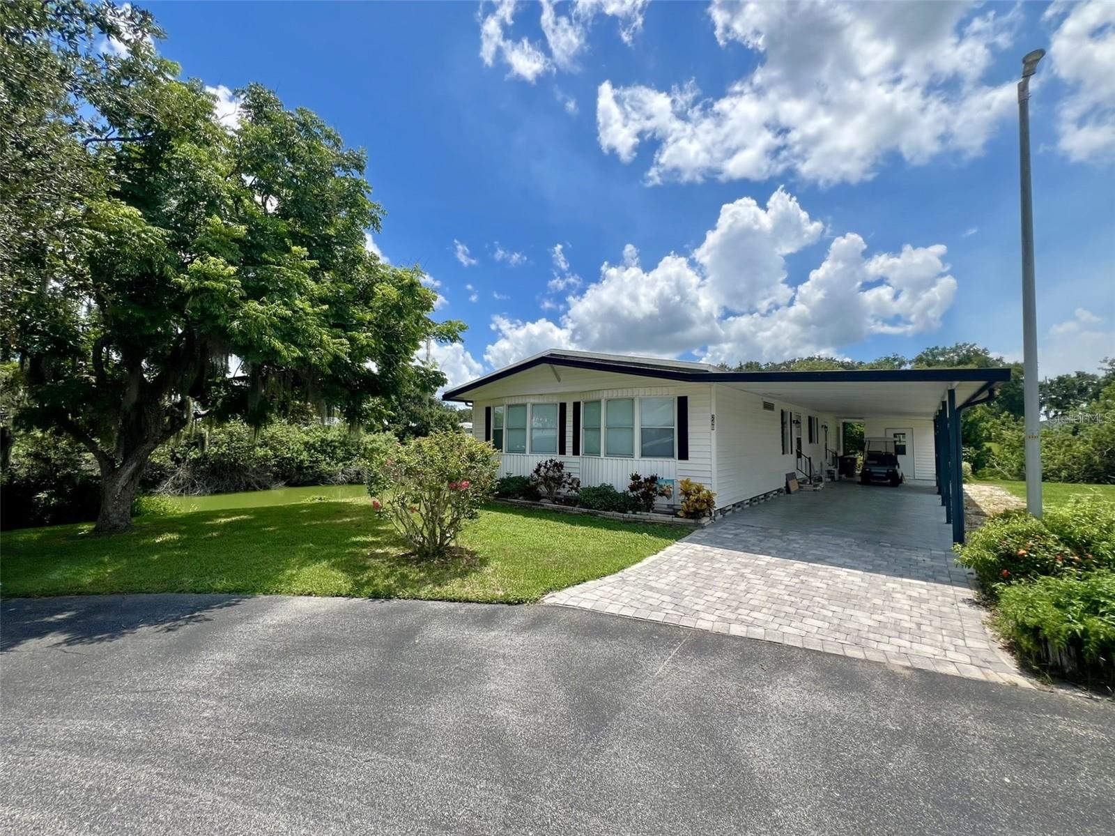 Discover your next home with unparalleled waterfront views in Floral Lakes, a vibrant 55+ Community in Bartow, FL. This spacious 2-bedroom, 2-bathroom manufactured home, located at the end of a peaceful cul-de-sac, offers stunning water frontage and a generous lot size. With approximately 1,704 square feet of living space, this residence is designed for comfortable and convenient living.
Step inside through one of the four entry points, including the main entrance that serves as a practical mudroom or "drop zone" with a laundry tub, upper cabinetry, and a closet (this was the original laundry room). The home features a popular split bedroom floor plan, providing privacy for you and your guests. The living room and Florida room boast newer double-pane windows that flood the space with natural light. The Florida room is a true retreat, offering serene views and its own dedicated mini-split air conditioning unit for year-round comfort. From here, you can step out onto a large wooden deck, perfect for relaxing and enjoying the tranquil surroundings. An 8x16 wood dock extends your outdoor living space, perfect for fishing or just soaking up the sun.
The heart of the home is the spacious kitchen, featuring an island cooktop with smooth burners, double wall ovens, a stainless-steel French door refrigerator, and a dishwasher. The space is a chef's delight with elegant granite countertops, a breakfast bar, and an abundance of cabinetry. The dining area is both functional and stylish, with built-in lighted shelving perfect for displaying your favorite collectibles.
The primary bedroom features mirrored doors on the walk-in closet and a private sliding glass door leading directly to the Florida room. Its en-suite bathroom has dual vanities, a relaxing garden tub, and a large tiled shower (with a glass door in storage, ready for installation). The second bedroom is generously sized with mirrored doors on the oversized closet and its own en-suite bathroom, which also serves as the guest bathroom with access from the common area, featuring a single vanity and a tub/shower combo.
Additional features include a long carport with room for at least one vehicle plus a golf cart, a spacious storage room with washer, dryer and shelving, and 6-panel interior doors throughout.
Located in central Florida, between Tampa and Orlando, this golf cart friendly community is near the Bartow Civic Center, Bartow Public Library, and Mary Holland Park. Here you OWN YOUR LAND (no lot rent) and pay low monthly HOA fees. The Floral Lakes community offers access to a stocked pond with community boat ramp and dock. Clubhouse amenities include recreation space, shuffleboard, putting green, and large heated swimming pool. Social clubs, dances, exercise, pot lucks, and MORE! Association approval is required for purchase. Call your Realtor today for more information and to schedule a showing!
