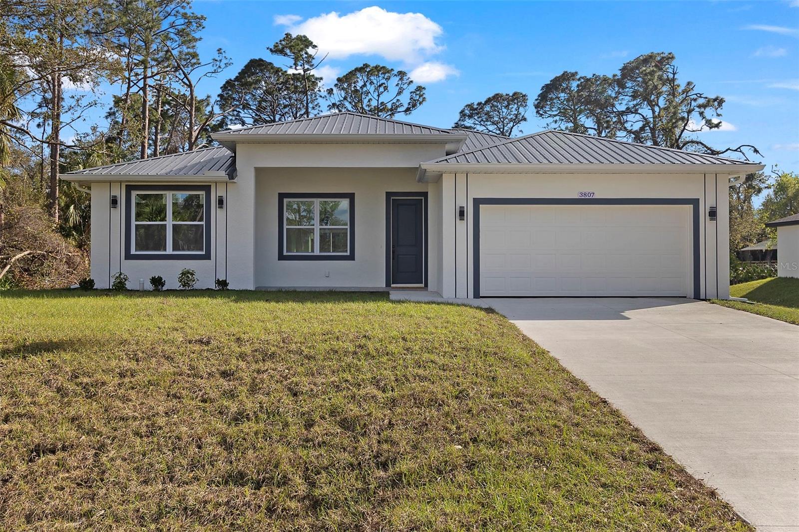 Stunning Move In Ready Modern 3-Bedroom Home – Built to Impress! Discover your dream home in this exquisite 3-bedroom, 2-bathroom residence, complete with a 2-car garage and an array of premium features designed for comfort, durability, and style.This Florida Green Building Coalition Certified Home combines energy efficiency with low-maintenance living – all in a NO flood zone location! Step inside to soaring 10-foot ceilings, accented by vaulted ceilings in key areas, creating a spacious and airy ambiance. The home boasts ceramic tile flooring throughout – extending to the front and back porches and even the bathroom walls – paired with modern 5.25’’ high baseboards and 8-foot doors for a sleek, contemporary look. Every detail shines, from the wood cabinets with soft-closing features to the granite countertops adorning the kitchen and bathrooms. Available now!
Built to withstand the elements, this home features a commercial-grade charcoal gray metal roof, concrete block walls, and impact-rated windows, doors, and garage door – offering peace of mind and lower insurance costs. The epoxy-coated garage floor adds a polished touch to the practical 2-car garage.
Energy efficiency is at the forefront with all LED lighting, remote ceiling fans in every room, and a builder-backed HVAC warranty. Enjoy modern light fixtures, plumbing fixtures, and door hardware that elevate the aesthetic, while spacious closets provide ample storage. Outside, the low-maintenance design lets you relax and enjoy the front and back porches, perfect for morning coffee or evening gatherings. With its top-tier construction and thoughtful upgrades, this move-in-ready gem is a rare find.