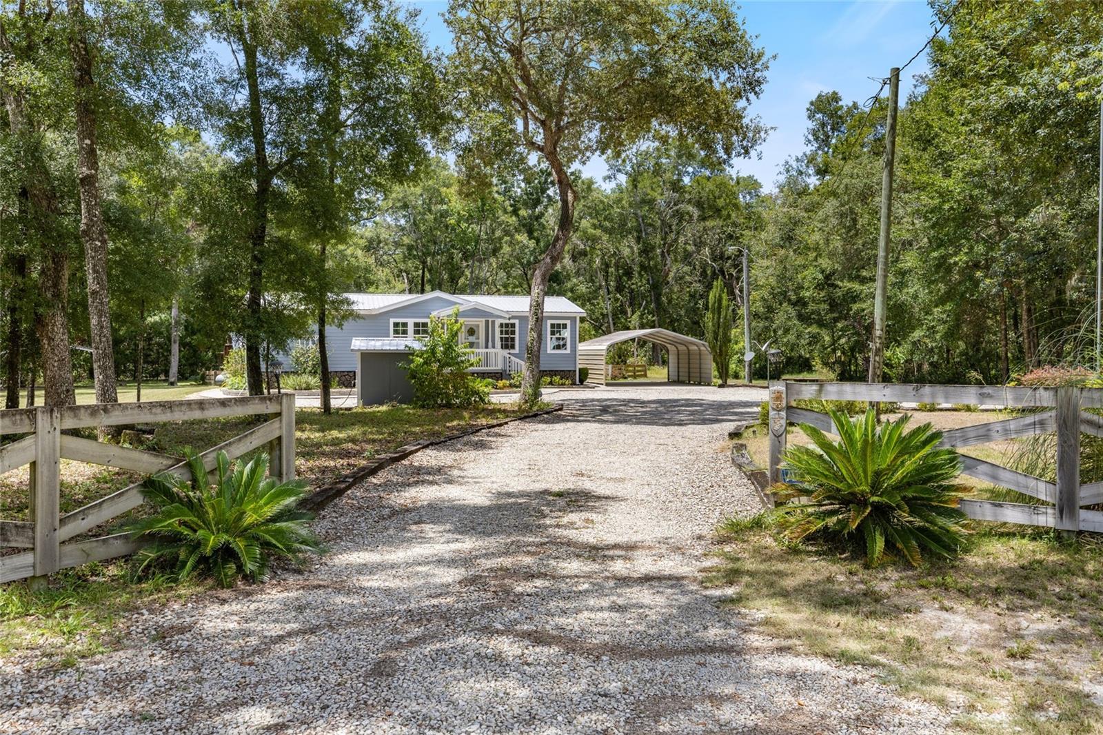 Enjoy the peace and privacy of country living just 4 minutes from town in this well-maintained 3-bedroom, 2-bath home in Chiefland, Florida. Tucked away on a mostly wooded parcel, this property offers the perfect blend of seclusion and convenience—plus easy access to the natural beauty of nearby Manatee Springs State Park and the Suwannee River. Built for durability and ease of maintenance, the home features a metal roof, Hardiplank siding, and an on-demand gas water heater. Inside, you'll find thoughtful touches like a custom butcher block kitchen island, double vanities in the primary bath, and a spacious laundry room with plenty of storage. A 10x28 sunroom addition brings in natural light and expands your living space, while both a screened back porch and a welcoming front porch let you enjoy the outdoors year-round. The fenced backyard is a peaceful retreat with a pond and waterfall feature, established landscaping, sidewalks, a garden area, gazebo, and a shed for extra storage. A double gravel driveway and detached 2-car carport make parking and access easy. Another great perk is NO HOA! Whether you're looking to garden, relax, or simply enjoy the quiet of rural life, this property offers the ideal setting—with plenty of modern comforts, space to roam, and nature right outside your door.