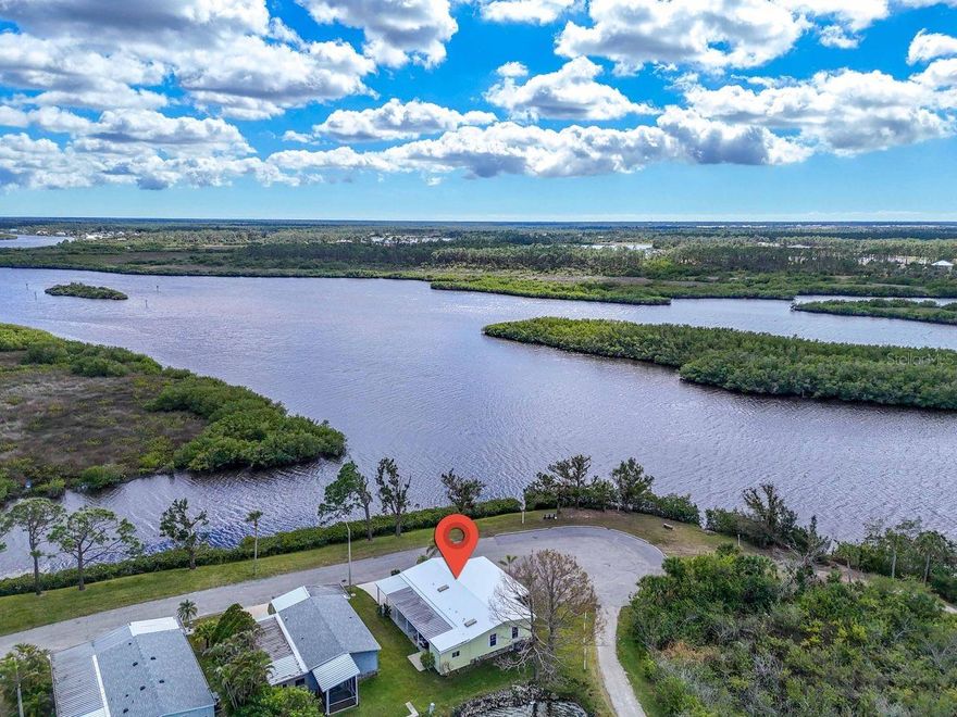 This is the LOCATION YOU HAVE BEEN WAITING FOR! Breathtaking water views of the Myakka River from this 2 bedroom, 2 bathroom home that backs to a lake, providing water views from every window in the house! Located in the 55+ community of Harbor Cove, this rare find is approximately 1,396 SF with an additional 272 SF west-facing lanai. Watch wading birds glide across the water every evening on their way to nesting grounds — a spectacle that adds magic to your everyday life. View glorious sunsets, and as the last house on the street, nothing will block your view. Launch a kayak or rent a boat slip at the marina for only $100 per year and explore scenic waterways all the way to the Gulf! Inside, find a large open layout with cathedral ceilings and lovely natural light thanks to some new PGT windows in the living room plus multiple new skylights. The roomy kitchen has plenty of counter space and cabinetry, plus a pantry. A sizeable primary suite contains a walk-in closet and French doors leading to the ensuite bathroom with large jacuzzi tub and walk-in shower. The guest room has sliding doors directly to the lanai and the hall bath is nearby. The small bonus room has a storage closet and handy desk area. Lots of parking space on the long driveway with carport and a shed with washer and dryer. The quality furnishings and golf cart are included in the sale and a new roof was just installed. The HOA fees are only $150 per month and include a Share, voting rights and access to incredible amenities including 2 swimming pools, spa, huge 2 story clubhouse overlooking the 90-slip marina, fitness center and various sports leagues and courts. Socialize and make friends at dances, shows, picnics, outings, craft classes, woodworking, etc. Located near shopping, dining, hospitals, parks, golf, spring training baseball stadiums and more. This property is surrounded by nature and is truly enchanting. Come and experience it for yourself!