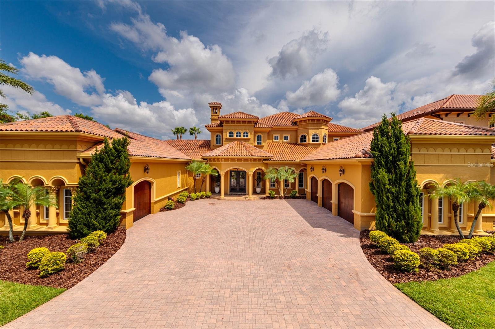 This Mediterranean-inspired home, rooted in historic European architecture, captures the essence of sun-soaked continental locales. Nestled within The Bayou Club, a private gated community, it blends timeless elegance with a modern touch. The resort-style pool serves as a stunning focal point, complemented by the lush backdrop of trees and a serene mangrove-lined waterway.Step inside to a grand parlor with soaring 22' ceilings and exquisite handcrafted details. The floor-to-ceiling windows illuminate the space and blur the line between inside and out. Adjacent lies a well-appointed office and a luxurious ground floor master suite featuring private pool access, a spa-like bathroom with dual walk-in closets, and a captivating open-air dual shower with 20' walls and a fountain.Craftsmanship shines throughout, from intricate crown molding and columns to designer lighting. A gourmet's dream, the kitchen boasts a commercial-sized Wolf gas range and premium Sub-Zero appliances, seamlessly flowing into a family room and dining space. Discover a private theater hidden behind pocket doors, complete with eight electric recliners, up to seven viewing screens, immersive sound, and an adjoining billiards and bar area with a sink, wine storage and a half pool bath . Outside, the resort-style pool beckons with its spa, swim-up bar, and inviting lounge areas. Four ensuite bedrooms, each with walk-in closets, span the home, with three situated upstairs. The upper floor also hosts a main laundry area with two washers and dryers. A generous balcony overlooks the pool and waterway, accessible via an external spiral staircase or private bedroom entrance.Unique to this residence is a canal dock, featuring two floating boat docks. Whether jet skiing, kayaking, or fishing for snook and redfish, this tidal canal offers an adventure that sometimes includes a visit from local manatees.Completing this haven is a circular paver driveway leading to four garage spaces, with one currently doubling as a gym. The main garage, spacious enough to accommodate car lifts, is ideal for enthusiasts.Welcome to your new indulgent resort — your home.