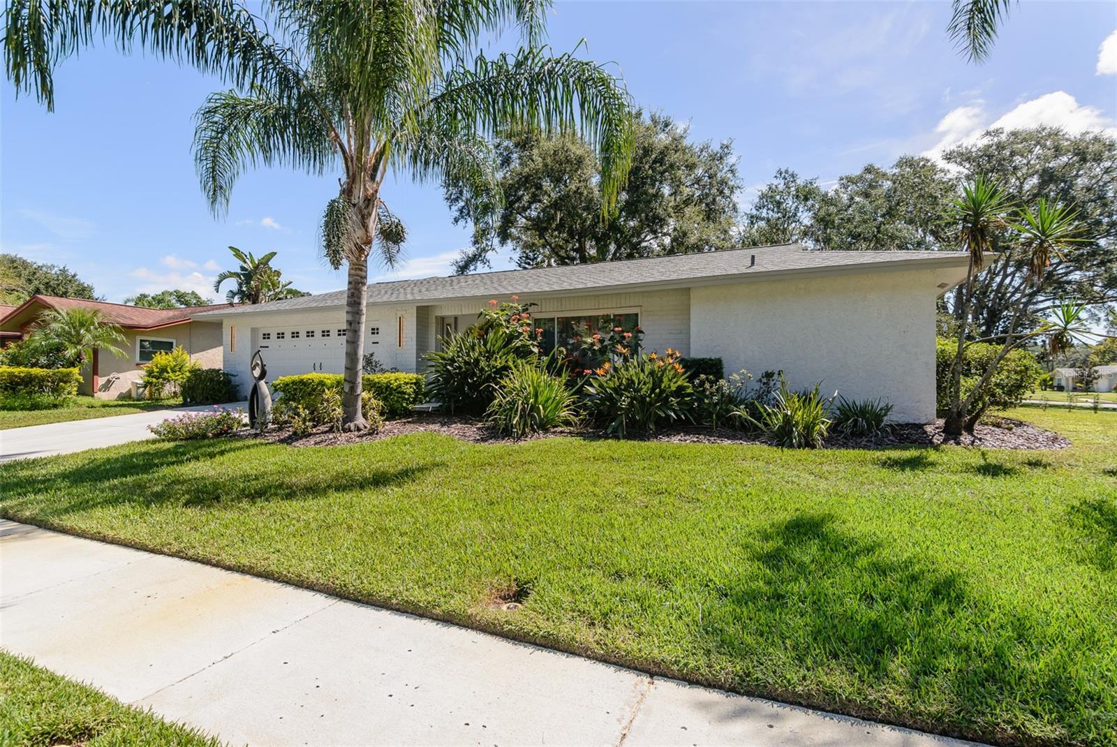 Looking for a move-in ready, completely updated 2Br/2Ba/2Gar home on a corner lot in a 55+ community? Look no further! Beautifully and fully updated baths and kitchen with new stainless refrigerator and range. Eight panels of Andersen Renewal hurricane rated sliding glass doors ($32,000) installed in August 2025 with views of the grand screened lanai and a charming brick-paved courtyard garden with fenced backyard. Impact rated windows installed in 2023. Shingle and flat roofs replaced in October 2023. Luxury vinyl plank flooring throughout. Crown molding in shared living spaces and 4 inch baseboards. Kitchen with granite countertops, marble mosaic backsplash, undermount sink, and under cabinet lighting opens to both living room and dining room. Electric fireplace in living room for chilly winter evenings. Split bedroom plan. The primary bedroom has a large walk-in closet and beautiful ensuite bath with stone countertop and walk-in shower. The guest bedroom with wall of closets abuts the guest bath with stone countertop, undermount sink, newer cabinet, tiled walls and tub rain-shower. Linen closet. New electric hot water heater 2025. Water softener. Newer washer and dryer in garage. Open all the sliding glass doors to bring the outdoors in during mild weather. Community pool and clubhouse with full kitchen, library, and billiard room. Low $500 annual HOA fee. Must own 2 years prior to leasing and a twelve month lease restriction with required HOA approval. Walkable to Lansbrook Golf Course and Suncoast YMCA with gym, pool, tennis courts, basketball, yoga classes, and exercise classes. Bike ride to John Chestnut Park with dog park, boat ramp and a boardwalk and tower for viewing Lake Tarpon. Also easy access to Pinellas Trail for walking and biking. Twenty minutes to Honeymoon Island State Park Beach.