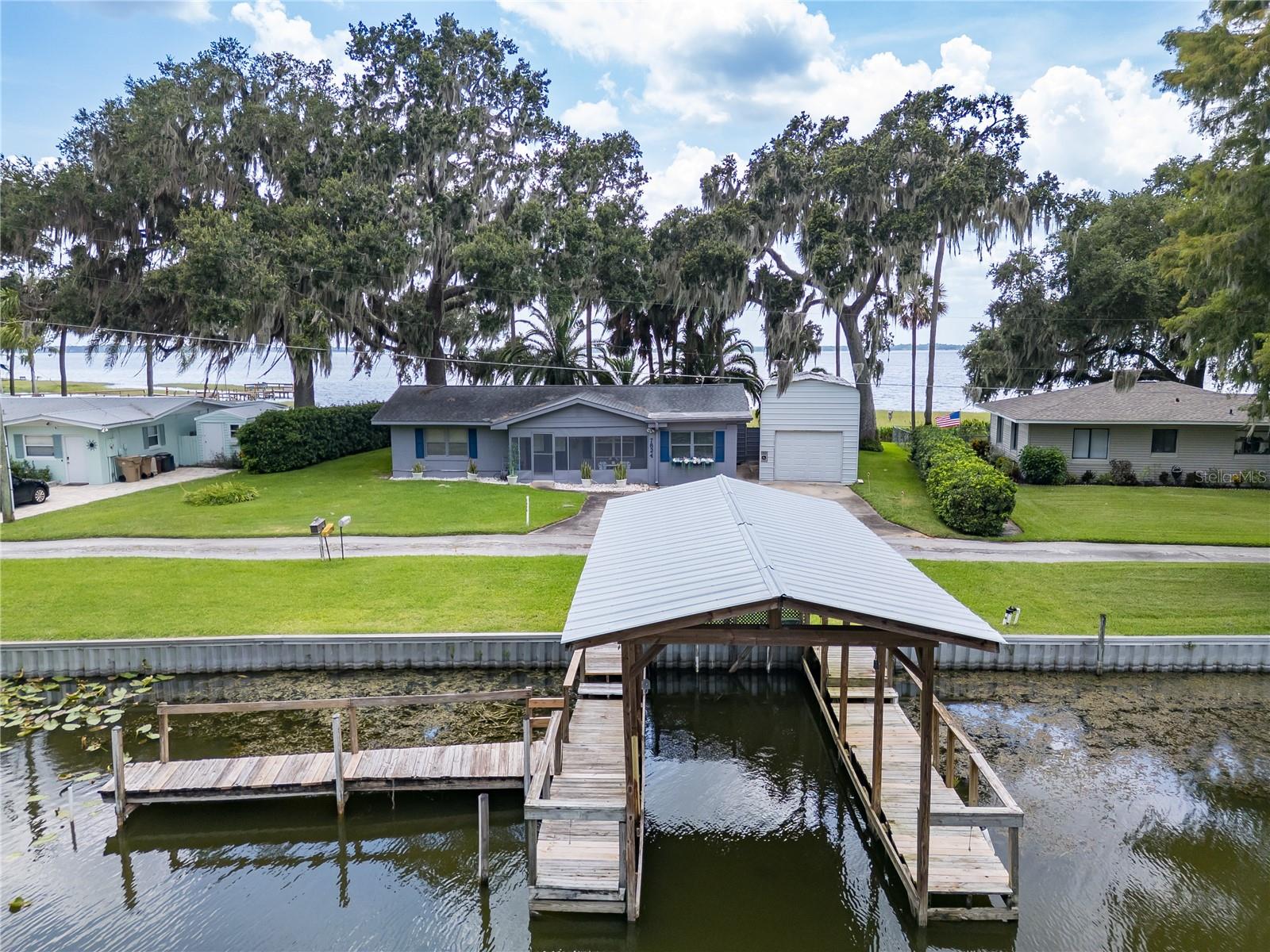 Unique DOUBLE waterfront property with Lake Griffin in the back yard and your lake access with a private dock and lift in the front yard. Located on a quiet private road, this 2 bedroom and 2 bathroom home with an office that could be converted to a 3rd bedroom has a functional layout, solid bones, and is move-in ready with opportunity for update to add equity. Whether you're looking for a full-time residence, weekend getaway, or a second home during the cold northern winters, this is a rare find with endless potential and true Florida Lakefront living.