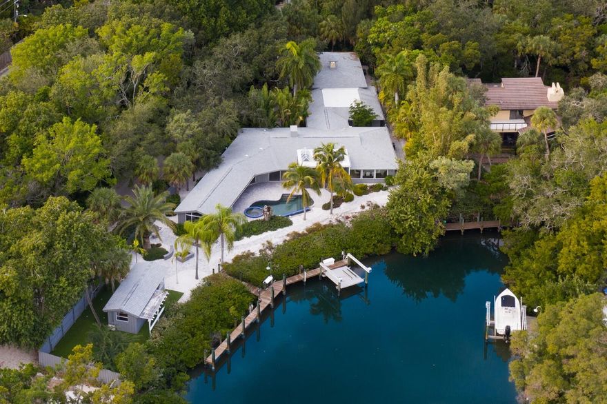 Motivated Seller! Bring An Offer. Discover the epitome of upscale coastal living in this breathtaking waterfront property, boasting a prime location with 160 feet of direct water access. This property is not just a home, it’s a masterpiece, designed by the illustrious Ralph Twitchell, a pioneer of the Sarasota School of Architecture. The home’s waterfront charm is complemented by a recently updated dock, accommodating a 59-foot boat and featuring a brand-new 10,000 lb lift.

Spanning 3,797 square feet, this single-level luxury abode offers four bedrooms and four bathrooms, presenting an aura of sophistication and comfort. The home underwent a tasteful renovation in 2019, enhancing its contemporary design while maximizing the stunning water views available from nearly every corner.

Step inside to find interiors that exude elegance, with soaring ceilings, European oak flooring, and a state-of-the-art kitchen equipped with Quartz countertops and stainless steel appliances. The living room, adorned with an electric fireplace, opens up to a spacious screened lanai – the perfect setting to savor the refreshing coastal breeze and mesmerizing water views.

The master suite is a haven of tranquility, offering serene views of the heated saltwater pool and spa. This private retreat includes two custom walk-in closets and an opulent bathroom with dual vanities, quartz counters, and chic, modern fixtures.

Adjacent to the master suite is a versatile bonus room, ready to transform into your dream space – be it a luxurious home office, an artist’s studio, a private gym, or a serene poolside lounge.

Car enthusiasts will appreciate the custom-built garage, spacious enough for four cars with potential for additional lifts. A newly renovated workout room with cork floors provides a dedicated space for fitness or meditation. The property also boasts a private putting area for golf aficionados and an air-conditioned “Fish Camp” complete with an outdoor kitchen, firepit, and the heated saltwater pool – creating an exclusive oasis for relaxation and entertainment.

Seize the opportunity to own this magnificent coastal gem. Elevate your lifestyle and make this dream home yours today!