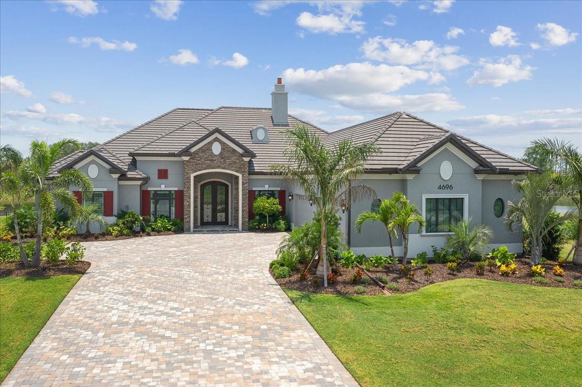 Luxury begins from the moment you enter this gated community, Adelaide. As you meander through palm tree lined streets, you are welcomed home to this pristine, custom-built stunner situated on a cul-de-sac, lake front, oversized lot. As you open the custom scrolled iron front doors, you are greeted with waterfront views, an open floor plan and warmth that envelopes you from the start. Luxury flooring throughout with high end finishes at every turn ensure a timeless design. The sprawling floorplan boasts 3 spacious guest suites, each with private en-suite. The most discerning buyer will enjoy the luxurious primary en-suite complete with dual vanities, claw foot tub and generous shower. Retreat for serenity to the elegant, bright and airy primary suite with sweeping lake and preserve views. Host simple dinners or elaborate soirees in your chef's kitchen replete with Thermador refrigerator and Bosch wall oven. Custom cabinetry "surprises" and a colossal pantry with secondary refrigerator delight with abundant storage. Technology lovers find joy knowing this smart home is controlled with Control4, has a new security system, surround sound, remote custom shades and more. Impact windows and doors, a fenced back yard and a 4-car garage and paver driveway offer peace of mind and ample space to spread out. This quiet neighborhood is nestled strategically within the community allowing for easy access to shopping, beaches, restaurants, airports and the interstate.