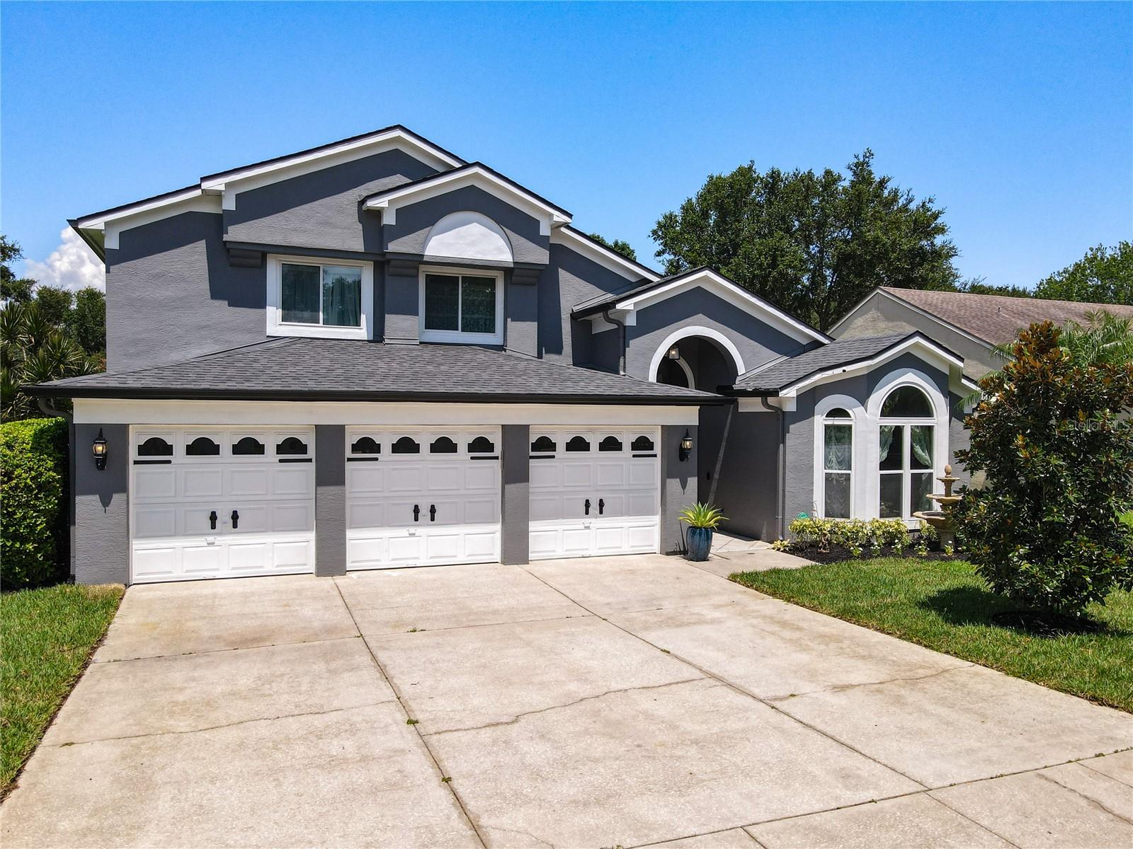 Welcome to 1319 Olympia Park Circle, a beautifully maintained 2,726 sq ft two-story residence nestled in the desirable Lake Olympia North Village in Ocoee, Florida. Set on a premium lot surrounded by lush landscaping, blooming garden beds, and mature trees, this home offers the perfect blend of elegance, comfort, and functionality. Arrive to manicured landscaping and a spacious 3-car garage—perfect for cars, golf carts, motorcycles, or even a compact watercraft. A beautifully landscaped with palm trees and water fountain front yard sets the tone for the elegance within. Inside the garage, an external electric vehicle (EV) charging station offers added convenience for today’s eco-conscious homeowner. Step through a custom decorative glass door into an open layout that flows effortlessly from the formal dining area to a bright sitting room with a large picture window overlooking the front yard and a classical water fountain—perfect for reading, relaxing, or enjoying piano music. The dramatic vaulted-ceiling family room is anchored by a double-sided wood-burning fireplace shared with the primary suite, creating warmth and ambiance year-round. A wide sliding glass door opens to the large screened-in sunroom, offering tranquil views of the lush backyard and/or seasonal pond. The open-concept gourmet kitchen is equipped with stainless steel appliances, granite countertops, premium cabinetry, a breakfast nook, and a walk-in pantry—perfect for both everyday living and entertaining. Adjacent is a cozy breakfast space with views of the serene backyard. The spacious main-floor primary suite overlooks the serene backyard/Garden accommodates a king-sized bed, nightstands, and a vanity area. The luxurious bathroom features dual vanities, a soaking garden tub, a walk-in shower, private water closet, and a large walk-in closet for optimal organization and comfort - your own peaceful retreat. Also located downstairs is the indoor laundry room with direct access to the garage—designed for ultimate convenience. An elegant staircase with wrought-iron railing leads to a versatile open loft—perfect as a home office, study area, game room, or second living space. Two upstairs guest bedrooms comfortably fit king-size beds and nightstands, and share a well-appointed bathroom with a shower/tub combo.
At the rear, an enclosed sunroom offers a peaceful space to relax, enjoy your morning coffee, or entertain with style. It’s the perfect spot to set up patio furniture, plants, or even a home yoga space. The private backyard with no rear neighbors provides serenity and privacy year-round. Upgrades & Updates Include: 2024 New Energy-Efficient AC,2020 Whole-Home Re-Pipe & Water Heater,2018 Roof Replacement, 2021 Exterior Paint & Gutters, Double-Pane Windows (2010),Solid Oak Hardwood Flooring,Custom Decorative Glass Door (2014)
Minutes from Downtown Winter Garden, the West Orange Trail, and major highways (FL-408, FL-429, Turnpike), you're just 20 minutes to Downtown Orlando and under 30 minutes to Disney or Universal. Ideal for commuters, families, or investors seeking both lifestyle and value. Whether you're upgrading, relocating, or investing, this home has it all—location, curb appeal, flexible living spaces, and resort-style privacy. Tucked in a quiet, beautifully maintained community with low HOA fees, this is more than a house—it’s a lifestyle.
Schedule your private tour today to experience the warmth, charm, and unbeatable value of 1319 Olympia Park Circle.