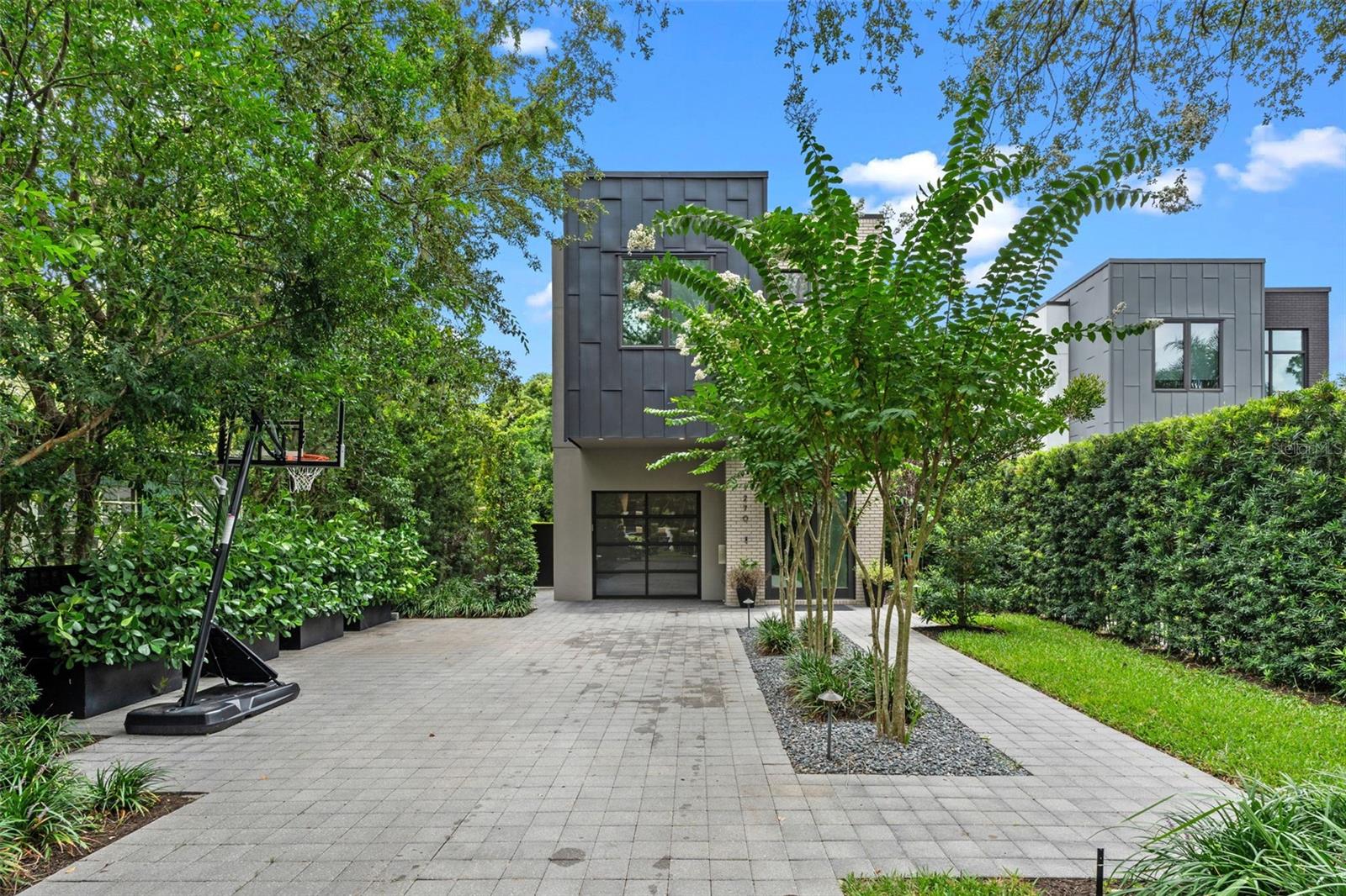 Modern Elegance in the Heart of Winter Park!
Located just a half-mile from the renowned shops and dining of Park Avenue, this architecturally striking residence blends luxury, modern design, and thoughtful functionality. Designed by Michael Wenrich and built by Jim Winters, every inch of this home reflects exceptional craftsmanship and elevated taste.
A long paver driveway welcomes you with ample guest parking and leads to a bold yet welcoming facade—complemented by large-scale windows and a sleek glass garage door. Natural light floods the interior, emphasizing the open-concept floor plan and seamless indoor-outdoor flow.
Step into a dramatic two-story foyer and be welcome inside to wide-plank wood flooring, modern lighting, tall baseboards, and a black metal staircase railing. The main living spaces are open and airy, anchored by a gas fireplace with a floor to ceiling mantle.
At the heart of the home is a show-stopping kitchen equipped with GE Monogram appliances, including a gas range and under-counter microwave. An eat-in[.n.,mmnm, waterfall island, complemented by under-cabinet lighting, a marble backsplash, and double-barrel under-mount sink with extendable faucet.
Tall glass doors and expansive windows blur the lines between inside and out. A collapsible sliding glass wall opens to the private backyard, featuring a cocktail pool, outdoor shower, lounge deck, and built-in plumbing for a future summer kitchen. Mature landscaping ensures privacy and serenity.
Upstairs, you’ll find three spacious en-suite bedrooms, each with custom closets, high ceilings, and stylish, neutral finishes. The second-floor laundry room adds convenience with matching cabinetry and a stainless utility sink.
The primary suite is a true retreat, offering direct access to a private upper deck overlooking the backyard. The spa-inspired bathroom features a dual-head glass-enclosed shower, floating double vanity, custom closets, and elegant lighting.
This home is a rare opportunity to own a piece of modern luxury just steps from everything Winter Park has to offer.
Schedule your private showing and experience this stunning home for yourself.