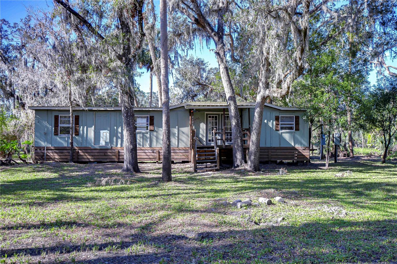 Discover the charm of peaceful, country living on this serene 2.37-acre property surrounded by towering trees, this private oasis offers the perfect blend of tranquility and opportunity. Step onto the welcoming covered front porch, perfect for relaxing with your favorite book or beverage. Inside, you’ll find an open layout with rustic wood accents that add warmth and character. The bright living area features French doors that open to another spacious porch, seamlessly blending indoor and outdoor living. The remodeled kitchen is equipped with ample cabinet and counter space, perfect for preparing meals, along with a range, and a generous pantry for storage. The dining room boasts natural light with multiple windows, offering picturesque views of the surrounding greenery. The oversized bedroom provides a comfortable retreat, while the bathroom has been updated with a new toilet and refinished shower. This property is a rare find with no HOA or CDD restrictions, giving you the flexibility to create the lifestyle you’ve always dreamed of. Whether you envision a quiet escape or a space to expand and customize, the possibilities are endless. Nestled away from busy roads but still just minutes from shopping and dining, this property offers the best of both worlds. Don’t miss your chance to own this delightful slice of countryside! Schedule your private showing today! Tour the home virtually with this link: my.matterport.com/show/?m=K74CAe8BY4k&mls=1