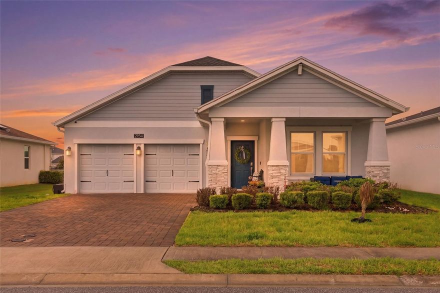 Nestled within the highly sought-after Providence Golf & Country Club, this beautifully upgraded 3-bedroom, 2-bathroom home at 2154 Camden Loop offers the perfect blend of comfort, style, and serene Florida living. Built in 2020 and spanning 2,084 square feet, this thoughtfully designed residence welcomes you with stunning curb appeal, featuring stone-covered columns, a spacious covered front porch, and a paver driveway and walkway.

As you step through the front door, you are immediately greeted by a versatile flex room on the right, perfect for a home office, playroom, or cozy sitting area. The hallway opens into an expansive and light-filled living space where the upgraded kitchen takes center stage. Designed with both functionality and style in mind, the kitchen features 42” wood cabinetry with crown molding, quartz countertops, a large island with breakfast bar seating, and sleek stainless steel appliances. The kitchen seamlessly overlooks the dining and living areas, making it ideal for entertaining, while the living room frames peaceful lake views that create a truly relaxing backdrop.

Tucked away on the left side of the home are two generously sized secondary bedrooms, each filled with natural light, complete with ceiling fans and plush carpeting. A well-appointed second bathroom offers wood-look tiled flooring, a shower/tub combination, and ample space for guests or family. The laundry room is conveniently located within this hallway for easy everyday use.

Privately situated at the rear of the home, the spacious primary suite is a true retreat, featuring tranquil lake views, a large walk-in closet, and a spa-like en-suite bathroom complete with tiled flooring, a walk-in shower, and a separate soaking tub.

Throughout the main living areas, you’ll find beautiful wood-look tile flooring that enhances both durability and design. Additional upgrades include a smart home wiring system, security system, insulated double-pane windows, and an irrigation system.

Step outside to enjoy Florida living at its finest with a screened-in rear lanai and covered porch overlooking the water, perfect for morning coffee or evening sunsets. The home also features a spacious 2-car garage and an inviting front porch ideal for enjoying the outdoors year-round.

Located within a gated, 24-hour guarded community, residents of Providence enjoy access to resort-style amenities including a championship golf course, clubhouse, pools, tennis courts, fitness center, playgrounds, walking trails, and an on-site restaurant. With its modern upgrades, functional layout, and picturesque setting, this home offers an exceptional opportunity to enjoy the best of Central Florida living.