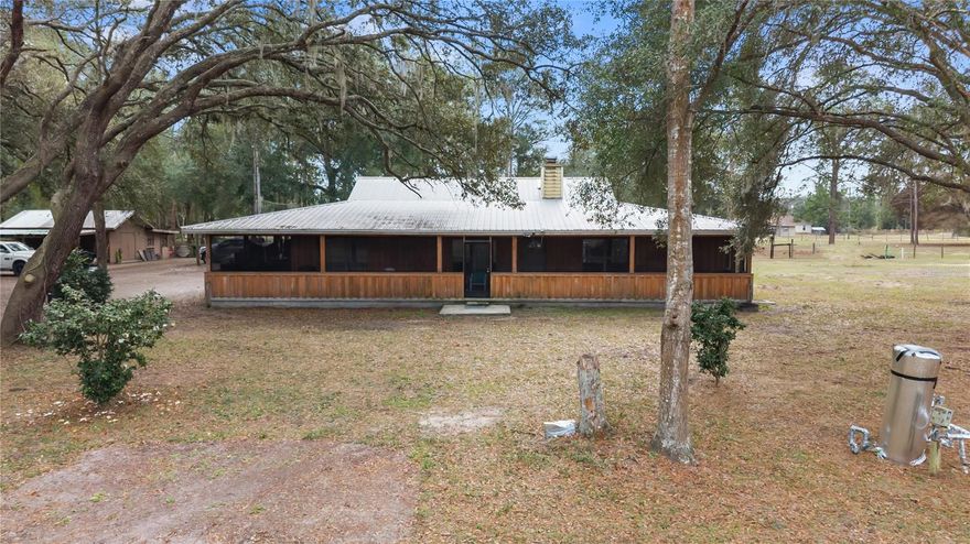 This homestead in Central Florida is a MUST SEE! NO HOA! Nestled among mature oaks, this spacious home sits on nearly 7 acres with endless possibilities! Offering privacy and versatility this custom-built Florida-style home is truly one of a kind.

The residence features a desirable split floor plan, abundant storage space, and a charming wraparound porch ideal for enjoying the natural surroundings. Inside, entertain with ease beside the wood-burning fireplace with stone façade or gather in the expansive 32’ x 28’ living room, perfect for hosting large gatherings or creating multiple living spaces. Designed for efficiency and durability, the home includes solar panels to help minimize energy costs, naturally resilient cypress siding, and brand-new dual 3.5-ton A/C units to keep the home comfortable year-round.

The land is well suited for animals and agricultural use, featuring an ample-sized shed with attached rabbit or chicken pen, two fenced pastures, and the option to allow livestock to roam throughout the fully fenced property. Enjoy the privacy of large adjacent wooded tracts of land and watch local wildlife.

Additional features include an impressive 2,600 sq ft workshop with slab foundation and high ceilings. Equipped with separate power, well, and septic, it offers incredible flexibility—ideal for equine stables, a home-based business, storage, or lease the space completely for passive income. The sale includes THREE adjacent parcels platted for up to EIGHT single-family lots, offering immediate development or investment opportunity if desired.

Conveniently located minutes from shopping, groceries, and prominent equestrian parks such as WEC and HITS, this home is also close to I-75, Florida Horse Park, Rainbow River, and numerous outdoor and recreational amenities. This rare property offers space, freedom, and opportunity—don’t miss your chance to make it yours.
