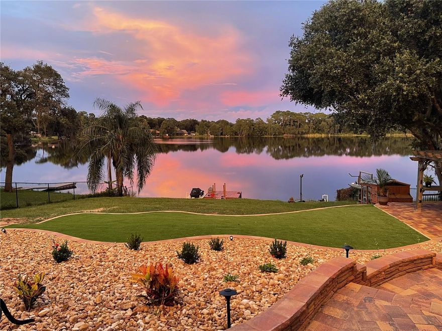 One or more photo(s) has been virtually staged. EXPERIENCE TRUE LAKEFRONT LIVING ON PRISTINE SPRING-FED LAKE IDLEWILD WITH PEACEFUL VIEWS.  LOCATED ON A .67 ACRE LOT THAT SLOPES DOWN WITH PAVER STAIRS,  FLOATING DOCK AND CONCRETE SLAB FOR BOAT ACCESS.  ** NEW ROOF 2026, ** WATER HEATER 2024.  WASHER DRYER 2023.  UPGRADED KITCHEN WITH ELEGANT QUARTZ COUNTERTOPS, BACKSPLASH, GORGEOUS SOFT CLOSE CABINETRY, PREMIUM GE CAFÉ APPLIANCES, CUSTOM LIGHT FIXTURES, BREAKFAST BAR, CUSTOM ISLAND WITH RECLAIMED WOOD.  A TRULY SHOWSTOPPER KITCHEN FOR THE HOME CHEF. LARGE DINING AREA WITH AWESOME VIEWS.   NO CARPET – ALL TILE.  SPLIT PLAN. As you walk-in the large foyer with cathedral ceilings flowing into the great room area, you will have gorgeous views immediately as you enter.  Primary bedroom has en-suite bath with separate vanities with granite countertops, water closet, walk-in closet WITH CUSTOM CABINETRY AND SHELVING, LARGE WALK-IN SHOWER, linen closet and pocket door.  GUEST SIDE OF HOME has two nice size bedrooms and large  closets with guest bathroom with granite and tub/shower combination.  Inside utility room, gutters, side entry garage, storage shed, landscape rock  in rear of home, paver patio, stairs and gazebo entertaining area.  WELL. SEPTIC. ATLAS PREMIUM SOUND SYSTEM,  ALARM SYSTEM. BUILT IN SPEAKERS. WATER SOFTENER.  Lake is great for kayaking, paddleboarding, fishing or simply relaxing by the lake.  CONVENIENT LOCATION CLOSE TO THE VILLAGES, SHOPPING AND ENTERTAINMENT. Schedule your private showing today and start living the Florida waterfront life you have been dreaming of.