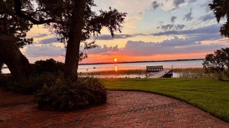 One or more photo(s) has been virtually staged. Lakefront Living – Your Waterfront Retreat Awaits Your Arrival! 

Welcome to this stunning 4-bedroom, 3-bathroom lakefront home on Lake Eustis, part of the highly sought-after Harris Chain of Lakes. Nestled on a quiet dead-end street in a peaceful, established neighborhood, this property offers the perfect blend of serenity, privacy, and natural beauty — all with no HOA restrictions.

Step inside to discover a warm and inviting interior featuring a wood-burning fireplace, formal living and dining rooms, a flexible den/office, and a sunlit breakfast nook. The spacious primary suite boasts an en suite bath and tranquil views, while multiple rooms throughout the home provide breathtaking west-facing sunset views over the lake just a few minutes boat ride (or other fun watersport equipment) to the Dora Canal or Dead River.

The large, well-equipped kitchen offers generous counter space and abundant cabinetry — perfect for entertaining and everyday living. Flooring throughout includes a mix of ceramic tile and carpet, complementing the home's comfortable and functional split plan layout.

Outside, enjoy beautifully established landscaping and your own private slice of paradise with both lake and canal access, plus a private boat dock — ideal for boating, fishing, or simply soaking in the Florida lifestyle. The stunning views at sunset create an experience that only nature can provide. From the brick patio or the dock, the relaxing vibe from this waterfront home is lakefront living at its finest.

With plenty of potential, this home is a rare opportunity to own a true waterfront gem in Central Florida. Schedule your private showing today!