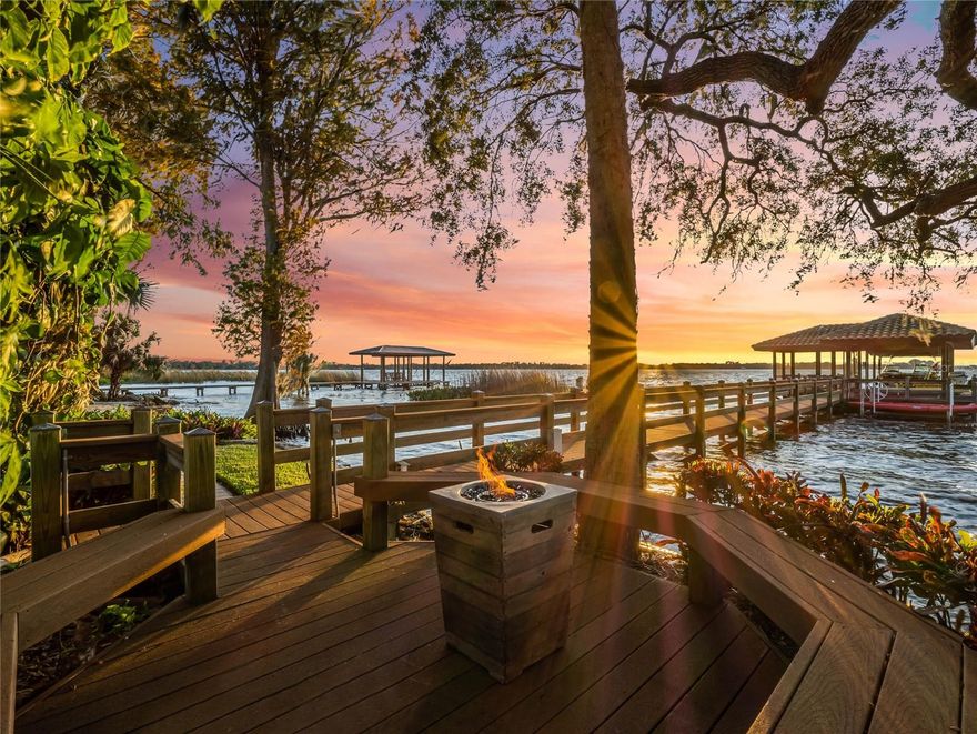 Nestled on the serene shores of Lake Dora within Florida's esteemed Harris Chain of Lakes, this enchanting Tuscan-inspired estate exudes European charm. The sprawling four-bedroom residence, enriched by an office space, epitomizes luxury living against a backdrop of lush tropical foliage and breathtaking sunsets.
Boasting over 120 feet of private shoreline, this haven features a private sandy beach, a boathouse, and a dock, inviting you to embrace waterfront living. Step into the refined oasis through a grand 10-foot mahogany cathedral door, instantly greeted by panoramic views of Lake Dora that mesmerize upon entry.
The spacious living room, adorned with 22-foot cathedral ceilings and exposed wooden beams, provides warmth with a gas fireplace, French doors, and abundant natural light. Stone arch doorways lead to an elegant dining area, seamlessly transitioning to a custom kitchen designed for culinary enthusiasts. European touches like the AGA gas stove, walnut-topped island, copper sinks, and granite countertops define this culinary haven.
The primary suite on the main floor offers breathtaking lake vistas, a luxurious spa-style bathroom, a custom walk-in closet, and additional amenities including a sauna, yoga room, and workout space. An office on the main floor overlooking the lake offers a tranquil work-from-home environment. 
Ascending via an elevator or a winding staircase to the second floor, discover three spacious bedrooms, each offering stunning lake views. Two of these bedrooms open onto private balconies, ideal for savoring sunsets with a glass of wine. One of these balconied bedrooms boasts its own en suite bathroom.
A three-car garage with epoxy finished floors offers plenty of space for parking and storage alongside your own built-in backup GENERAC generator.
The outdoor features include a screened saltwater pool, raised spa with a waterfall, an outdoor kitchen, a lakeside gas fire pit, and a lighted dock with boathouse and three lifts, inviting endless waterfront adventures. Downtown Mount Dora and Tavares are only a short boat ride away, five and ten minutes respectively. 
The exclusive gated community of Deer Island is a natural 400-acre island surrounded by Lake Dora and Lake Beauclair. It features an awe-inspiring, privately-owned 18-hole championship golf course, ranking an impressive 24th on the 2023 Golfer's Choice list. This location offers close proximity to historic downtown Mount Dora as well as Tavares, known as America’s Seaplane Capital, where waterfront dining and boutique shopping is abundant, and Orlando is a mere 45-minute drive away.