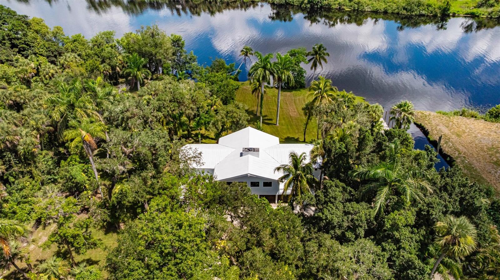 Exquisite Luxury Riverfront Estate in Alva! Welcome to this remarkable riverfront estate nestled on nearly 6 acres of pristine land in the heart of Alva. This one-of-a-kind property boasts two beautifully renovated residences, offering a unique blend of luxury living, privacy, and income potential. Main Residence: The primary home features 3 spacious bedrooms and 2 modern bathrooms, with 1,742 sq. ft. of thoughtfully designed living space. Recently renovated throughout, it showcases cathedral ceilings with exposed wood beams, impact-resistant windows, and an expansive screened balcony offering panoramic views of the Caloosahatchee River. The gourmet kitchen is outfitted with top-of-the-line appliances, sleek finishes, and custom cabinetry. Additional highlights include ultra-modern bathrooms, over five covered parking spaces, and uninterrupted river views from nearly every room. Sitting at nearly 13 feet of elevation, the property provides peace of mind with excellent flood protection. Waterfront Features: Enjoy over 170 feet of direct river frontage, complemented by a private canal with a custom dock accommodating vessels up to 80 feet. Complete with water and electrical hookups, this deep-water dock also features a private on-site boat ramp, providing unmatched convenience. Guest House: The secondary residence, located at the front of the estate, is a fully renovated 3-bedroom, 2-bathroom home offering 1,275 sq. ft. of living space. Currently operating as a highly successful vacation rental, this guest house offers excellent income-generating potential while maintaining privacy thanks to the generous acreage separating the two homes. Equestrian Amenities: Ideal for equestrian enthusiasts, the property includes a well-maintained horse barn and ample fenced acreage for horses to roam freely. Whether you're seeking a serene and ultra-modern riverfront retreat with yacht access and equestrian facilities, or a proven income-producing investment with multiple opportunities for expansion, this estate offers the best of both worlds.