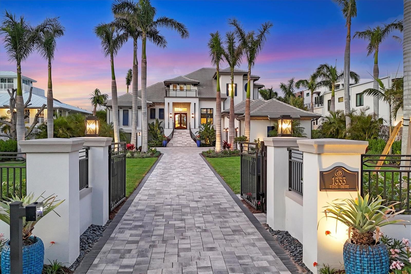 On pristine boating waters in Harbor Acres, 1333 Vista Drive is a luxurious and inviting retreat designed for those who appreciate extraordinary craftsmanship, effortless entertaining and tranquility of coastal living. From the moment you arrive, the home’s dramatic setback, striking elevation and lush, mature landscaping set the stage for the sophisticated casual elegance within. Modern coastal architecture and a stunning glass double-door lead to the welcoming foyer featuring a custom-designed tile floor. The living room showcases a wine display case, an accent wall with custom trim, and glass doors leading to the terrace with water views. The adjacent dining room, with a beamed ceiling and designer chandelier, overlooks the water. The chef’s kitchen is a masterpiece, boasting custom cabinetry, a herringbone tile accent wall, and Wolf and Sub-Zero appliances. A central island with quartz countertops and pendant lighting anchors the space, while the butler’s pantry offers additional convenience and storage. The open family room is framed by expansive windows and sliding doors that seamlessly connect indoor and outdoor living. An office with a built-in Murphy bed, custom desk, and terrace access offers versatility as a workspace or additional bedroom. The primary suite is a sanctuary, featuring a seating area with bay windows, a double tray ceiling with custom inlay and engineered wood floors. Its spa-inspired bath is a retreat, with an expansive Roman shower with glass walls, a freestanding soaking tub, floating vanities with quartz countertops and two custom walk-in closets. A lighted staircase with custom-trimmed walls leads to the upper level, where a sophisticated bonus room with a wet bar and zero-corner sliders opens onto a wraparound terrace with breathtaking bay views. Three guest suites, each with walk-in closets, well-appointed baths and private terrace access, ensure unparalleled privacy and comfort. The outdoor amenities elevate this home’s resort-like ambiance to another level. Travertine stairs lead to a raised spa that cascades into the pool, complete with integrated seating, a sun shelf and water features. Expansive lounging and dining areas, along with a fully equipped outdoor kitchen featuring an island with a waterfall-edge stone counter, provide the ideal setting for alfresco entertaining against a serene waterfront backdrop. Professionally designed landscaping and lighting enhance the tranquil setting. For boating enthusiasts, this home is unmatched. The recently inspected seawall is in pristine condition, and the dock is equipped with electricity, a 15,000-pound boat lift and dual wave runner lifts. The residence is equipped with a three-stop elevator, a thoughtfully designed laundry room, a three-car garage with custom organization and an additional garage door that opens to an enormous garage and storage space. This remarkable waterfront home in Harbor Acres offers an effortless blend of sophistication, relaxation and coastal charm. Designed for boaters, entertainers, and those who value luxury and comfort, this home offers an unmatched lifestyle just minutes from downtown Sarasota, Southside Village, Selby Gardens and world-famous beaches. 1333 Vista Drive is the ultimate waterfront retreat in the ultimate location.