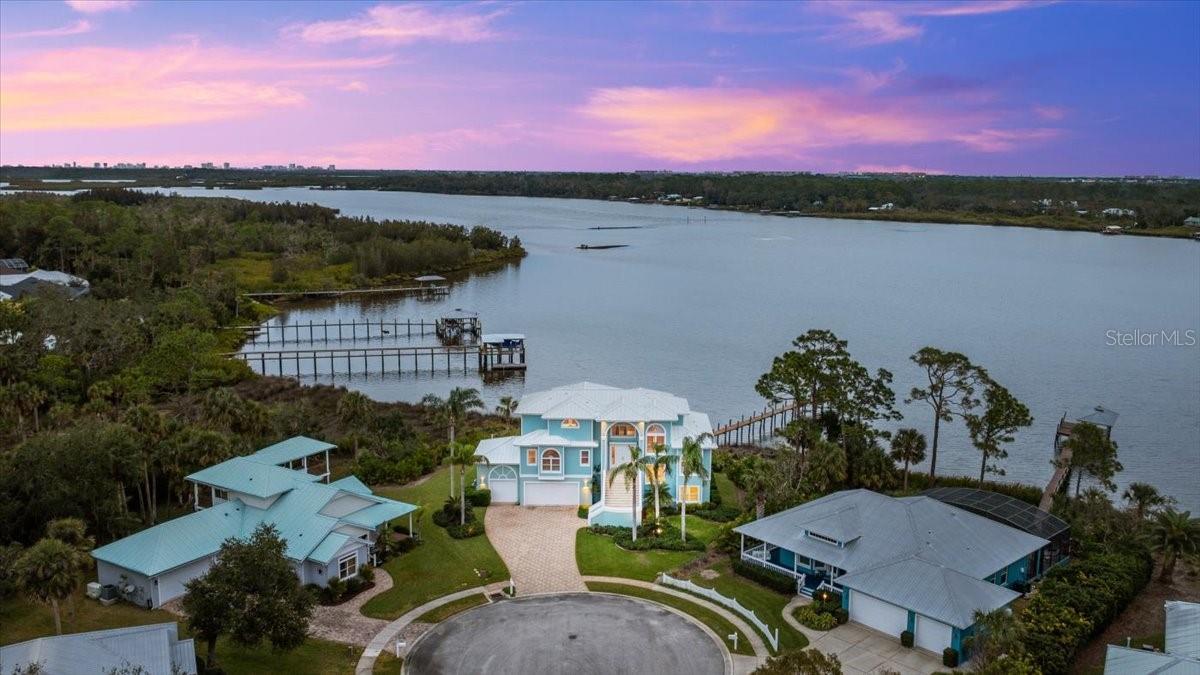 Luxury Waterfront Key West Style Home in Gated Osprey Cove! Discover a slice of paradise in this stunning waterfront Key West-style home nestled in the exclusive gated community of Osprey Cove in New Smyrna Beach. Located on the serene Turnbull Bay, this luxurious property offers a unique blend of elegance and coastal charm. The pavered concrete driveway and meticulous landscaping set the tone as you approach this exceptional home, crowned with a durable metal roof. Enter through the second floor to find the heart of the home, featuring a spacious living room, dining room, and a cozy two-sided fireplace. The chef's kitchen is a masterpiece, boasting a center island, ample cabinet and counter space, and breathtaking water views. Adjacent to the living spaces, an office offers the perfect spot for work or reflection, while two bedrooms, each with en-suite baths, and an additional half bath ensure effortless entertaining. The top floor is dedicated to the luxurious master suite, complete with a spa-like private bath, an expansive walk-in closet, and a private balcony where you can savor the tranquil waterfront vistas. Take the stairs or elevator to the ground floor, where you'll find a versatile family room, additional living space, an office, and a large screened patio. Step outside to your private dock that leads to the water's edge, complete with an outdoor fireplace perfect for relaxing evenings under the stars. The three-car garage ensures plenty of space for vehicles and storage. This home is a waterfront dream come true, offering luxurious living, unparalleled views, and a seamless connection to the natural beauty of Turnbull Bay. Don't miss the opportunity to make this extraordinary property your own! Square footage received from tax rolls. All information recorded in the MLS intended to be accurate but cannot be guaranteed.
