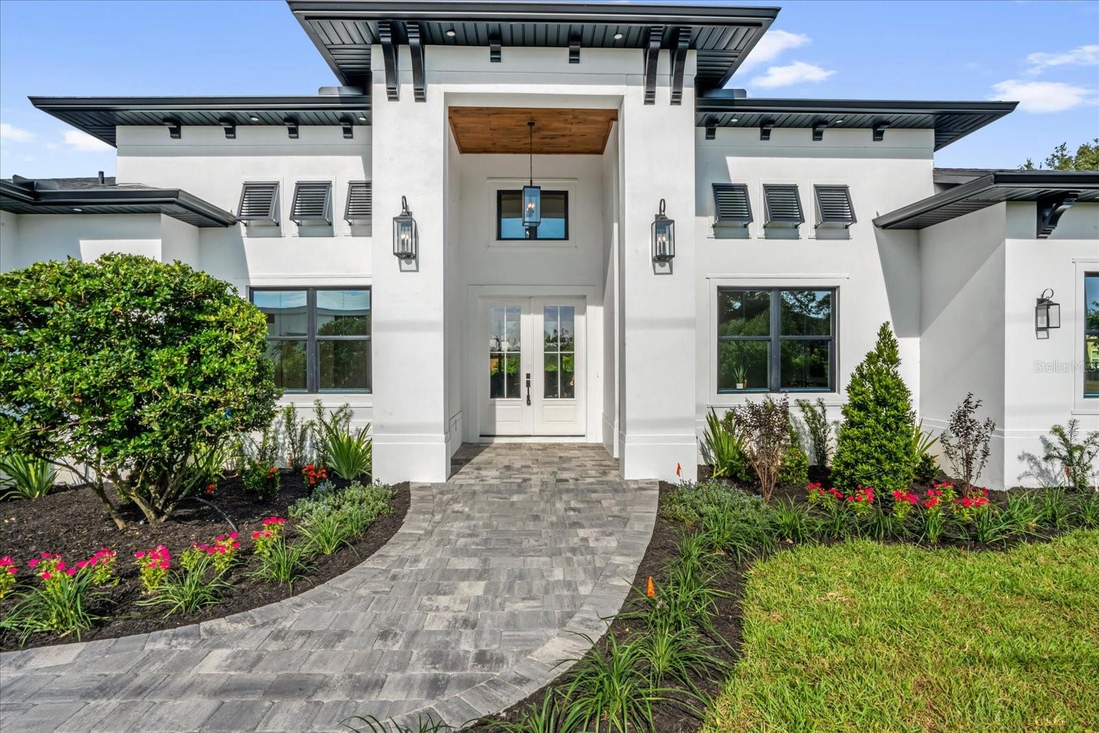 Fantastic New Construction Custom Home in Winter Garden, one of Central Florida’s most sought-after locations. Step into a world of excellence in this single story modern masterpiece. With soaring ceilings and high-end finishes throughout this home is sure to appeal to a wide range of buyers. With over 4420 square feet of conditioned living space on a half-acre lot there is ample room for everyone. Each of the 5 bedrooms are en-suite with the spa like master the jewel in the crown. With engineered hardwood and porcelain tile floors throughout, the entire home is carpet free making it a hit with pets and during allergy season. The home is turn-key and move-in ready all you need to do is turn up and unpack your bags before enjoying a dip in the beautiful back-yard pool. All the extras come as standard in this incredible home from the beautiful hardwood floors to the Bowers & Wilkins surround sound speakers in two rooms! But let us start with the kitchen where you will find top of class Thermador appliances (Wi-Fi enabled) including a double wall oven, under counter island microwave, 48-inch drop in stove and column refrigerator & freezer. Speaking of islands, did I mention the stunning Cambria quartz top on the oversized island with room enough to sit six adults in comfort! Everything about this home is big…plenty of room for everybody whether it is sitting at the kitchen island or sitting in the breakfast nook, the living room or even out on either of the back patios space abounds! Flexibility comes in the form of the bedroom at the back of the home which could also be used as a media/theater room. This room, along with the main living room are set up with surround sound. In the living room, a 7.1 ceiling speaker set up has been installed as standard and in the back bedroom, 4 surround sound ceiling speakers have been installed with pre wires for front left, right & center channels. The ceiling on the lanai has also been pre-wired. The home has been designed with either 5 bedrooms and an Office or 4 bedrooms, an Office and a Media Room. As an added convenience, the garage doors have been insulated and high lifts have been utilized to facilitate standing on the bed of a truck whilst inside the garage. A 220 supply has also been installed for use with electric vehicles. Finally, the garage floor has been finished with a polyaspartic finish. Outside, the home benefits from a generous landscaping package, a pool & spa, an outdoor kitchen/grill, tongue & grooved ceilings, and a wonderful west facing aspect. In all honesty, the pictures as wonderful as they are, are no substitute for seeing this home. Currently, Winter Garden has very few new construction custom homes in move in ready condition. If you are looking for something special with all the bells and whistles included as standard on an over-sized lot with no HOA (yes you can bring your RV or your Boat or, both!!) then why not come and visit this home in person. You surely will not be disappointed! The listing Broker is a Principal of 7163 LLC and has a material interest in the property.