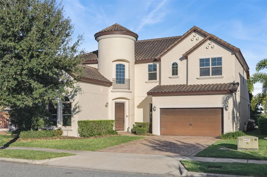 Discover refined living in this impressive 5-bedroom, 4-bathroom Spanish-style estate home, beautifully positioned on a serene waterfront lot with peaceful conservation views and nightly Disney fireworks from your own backyard. This exceptional home blends elegance, comfort, and energy efficiency throughout its thoughtfully designed layout.

Step through the grand, elegant entrance into a soaring cathedral-ceiling foyer that leads to spacious formal and casual gathering areas. The formal dining room sets the tone for entertaining, while the gourmet kitchen is a true showpiece—featuring an oversized island, dry bar, walk-in pantry, solid wood cabinets, granite countertops, elegant backsplash, and high-end stainless steel appliances. A striking stone accent wall with an electric fireplace adds warmth and style to the main living area, which opens through French doors to breathtaking water and conservation views.

The first floor includes a comfortable guest bedroom with a walk-in closet, a full guest bath with convenient pool access, and a luxurious primary suite. The primary bedroom offers a huge walk-in closet, and a spa-inspired ensuite bathroom with garden tub, expansive walk-in shower with multiple rain shower heads, and dual vanities.

Upstairs, a spacious loft with surround sound showcases elevated views of the water and conservation area—perfect for a media room or game space. On one side of the loft sits a private bedroom with its own full bath, ideal for guests or extended family. On the opposite side are two additional bedrooms connected by a Jack-and-Jill bathroom, providing comfort and privacy for everyone.

Additional highlights include a tile roof, oversized garage, paver driveway, Smart thermostat, water softener and filtration system, and energy-efficient features for year-round comfort.

Located in the highly desirable Watermark community, residents enjoy resort-style amenities including a sparkling pool, water park, cabanas, BBQ areas, playground, dog park, tennis and basketball courts, clubhouse with rooftop deck, weekly community activities, fitness center, and scenic walking trails.

All of this—just minutes from top-rated schools, dining, shopping, Orange County National Golf Course, and Disney World.

A perfect blend of elegance, comfort, and unmatched location—this waterfront estate is truly a must-see.