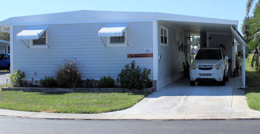 Looking out over the golf course toward the 5th green in Palm Hill Mobile Home Park is where you will find this charming mobile home.    The longtime owner has maintained her home immaculately.   There are two bedrooms, two bathrooms and an open Florida Room all included in the 1056 sq. feet under central air.  Residents and renters all enjoy the resort like opportunities offered in Palm Hill, a premier 55+ community. From swimming pools, jacuzzies, pickle ball, tennis, shuffleboard, bocce ball, golf, to two clubhouses with many social activities, you can be as active as you wish.  The one monthly maintenance fee of $554 includes lawn care, trash and recycling services, water, sewer, cable, and internet. This inviting mobile home boasts a spacious, open floor plan that seamlessly connects the living area, dining space and kitchen creating a welcoming atmosphere for both relaxation and entertainment.  In 2019 the old vapor barrier was completely replaced.  Also, in 2019 luxury vinyl floors (with new sub floors) were added in the galley kitchen, dining, and living room.  The galley kitchen is conveniently situated off the carport.  Upper and lower attractive wooden cabinets provide ample storage space.  Pull out drawers create wonderful organization. Attractive countertops with illuminating lighting give ample work area.  A smooth top range, overhead microwave, and refrigerator are designed for easy use.  A window above the sink offers a view of the golf course while you work in the kitchen.   Directly behind the kitchen is the dining area and the living area.  The area is open with the dining on one side and the living area on the other side.  The living area and kitchen both have access to the enclosed Florida Room. This entire space is covered by central air conditioning.   Large windows on all sides of the room bring delightful light inside.  What a beautiful spot to enjoy the greenery of the golf course beyond.  Floors here are also luxury vinyl.  An attractive door on one side provides an exit to the outside and to the street. The Florida Room is a highlight, perfect for enjoying the beautiful views and year-round sunshine in comfort.  Both bedrooms are generously sized and offer adequate closet space.  The ensuite bath features shower, and an updated vanity, while the guest bath has tub with shower and sink with ample countertop. Ceiling fans in both bedrooms and the living room provide pleasant air flow. The central a/c was new in 2022.   Please note that the home is sold mainly unfurnished.  The owner will leave the furniture in the primary bedroom and will provide notice of what additional furniture will stay.  A generous size patio overlooks the golf course. What an enjoyable spot to relax with friends   and enjoy the scenic surroundings of the golf course.  The home has a pleasing look with light-colored siding, roof over, and a side extension off the driveway.  A utility space at the end of the carport includes storage areas and connections for a washer and dryer.   This enticing golf front property includes a share of $35,000 in the list price.   This one shouldn’t last so please call for an appointment.
