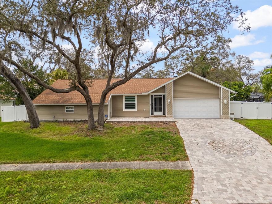 COMPLETELY REMODELED!  Lovely 3-bedroom, 2-bath home with a fully fenced (white vinyl) backyard, and a 2-car garage.   A new A/C and patio pavers were installed in 2013, a new water heater and hurricane-rated garage door were installed in 2016, a NEW ROOF was installed in 2020, and NEW WINDOWS & DOORS were installed in 2024.  The flooring is luxury vinyl tile throughout.  The remodeled kitchen features white cabinets with white solid-surface countertops, stainless steel appliances and double sink.  The hall area features a skylight, and the living room and two bedrooms have beautiful chandeliers.  This home is perfectly situated on a private wooded lot with a screened pool and a covered lanai in the friendly community of Eniswood.  HOA membership is completely optional.  This community is close to quaint downtown Palm Harbor with dining, entertainment, schools, and parks.  It is a short walk or bike ride to Palm Harbor University and the Pinellas Trail, and a short drive to Honeymoon Island.