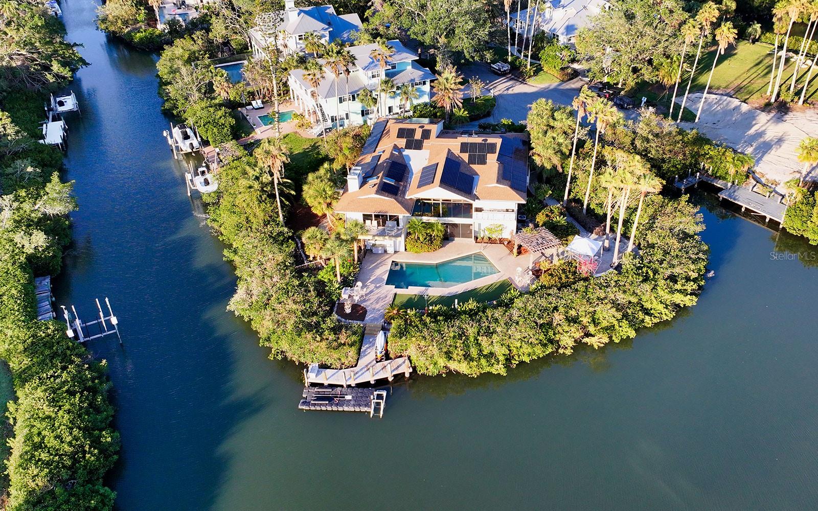 South Sarasota waterfront property surrounded by 312-ft. of water on three sides feels like living on a private island. Serene privacy on a cul de sac in the secluded South Creek community directly across from Oscar Scherer State Park and just 5 minutes to Pine View School for the Gifted. Located between Sarasota and Venice with easy access to the best amenities in both communities including beaches, shopping, dining, arts, medical and personal services. This “island” playground is an outdoor enthusiast’s delight. Private dock with kayak/paddleboard launch provides easy access to Sarasota’s coastal waterways for endless days enjoying Florida’s year-round sun and fun. Take a kayak trip to Nokomis Breakfast Cottage, Oscar Scherer State Park or secret mangrove tunnels. Relax on the back porch and be on the lookout for manatees, dolphins, pelicans and ospreys. A five-minute drive takes you to Nokomis Beach. The nearby Legacy Trail offers over 20 miles of rails-to-trails paved cycling paths. Spectacular sunsets are a daily celebration. The 5,233 sq. ft. residence has four bedrooms and three-and-a-half baths. Living areas include formal living room with cathedral ceiling and built-in Bose sound system, formal dining room, family room with wood-burning fireplace and four exterior balconies. The ground floor has various climate-controlled rooms and screened in areas, laundry room and pool shower. Outdoor amenities include heated swimming pool, pergola with bench swings, bocce court and dock. South Creek is a gated community with easy access to US 41 and I-75. This residence is on the same street as the community amenities which include tennis courts, basketball, playground, day dock and night security gate. The singular combination of location, waterfront and size make this a desirable property for an exceptional lifestyle.