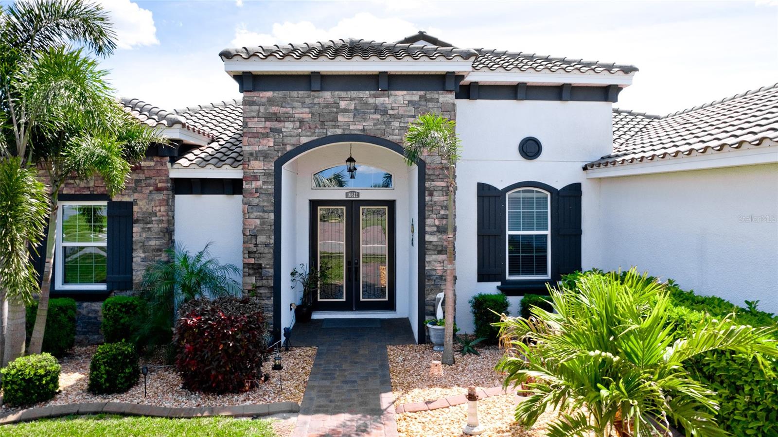 This beautiful Lory model is in the sought after Rye Wilderness Estates. Double glass eight foot doors welcome you into this gorgeous open floor plan with ten foot ceilings with crown molding, 4 bedrooms, 4 bathrooms, tile roof, 3 car garage with paver driveway on a 1/2 acre lot all make this the ideal home. Once inside, you'll find the formal dining/sitting room to the right, continuing to the wide open great room with impressive stone feature wall and accompanying stylish wall shelves, large tray ceiling with crown molding, then on to the impressive gourmet kitchen, featuring a long center island, designer backsplash, top of the line stainless steel appliances, artistic vented hood, under counter lighting, a spacious walk in pantry, solid wood grey cabinetry with pullouts, granite countertops, and an induction cooktop. The interior opens to an exquisite large custom pool and brand new spa with paver lanai, custom built outdoor kitchen with seating area and fireplace under roof with enclosed pool screen. This secluded oasis offers lots of privacy with its exquisite landscaping. Double eight foot doors guard the oversize master suite with impressive custom walk in closets, luxurious master bath with dual vanities, relaxing garden tub, and oversize walk in shower. On the other side of the house there are two suites with walk in closets and personal full bathrooms, and a fourth additional bedroom with bathroom that serves as a pool bath. NO CDD's, LOW HOA's. The community is known for its generous lot sizes, proximity to schools, shopping, dining, entertainment and Beaches and amenities such as courts and a playground.