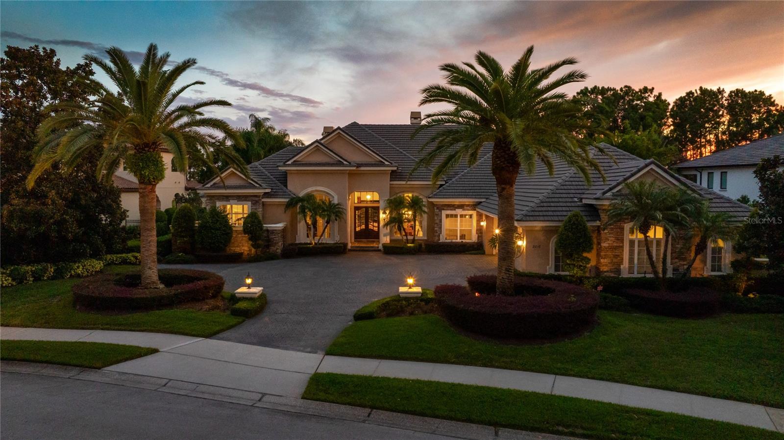 Perfectly positioned on over two acres within the prestigious gated community of Loch Leven, this lake front estate embodies timeless elegance, architectural grandeur, and the ultimate expression of Central Florida lakefront living. From the moment you arrive, the home commands attention with its stately facade, oversized 4-car garage and meticulously manicured grounds that set the stage for the extraordinary lifestyle within. Inside, the residence unfolds across a single expansive level, designed for both effortless flow and breathtaking visual impact. Walls of glass capture sweeping views of the water, filling each space with natural light and creating a seamless connection between indoors and out. At the heart of the home, the chef's kitchen is a culinary masterpiece, anchored by a massive center island and outfitted with professional-grade appliances, custom cabinetry, and expansive prep and entertaining space. Its open design allows for effortless transitions into adjoining living areas, making it the true gathering place of the home. The primary suite is a sanctuary of indulgence, oriented to maximize privacy and panoramic lake views. Its spa-inspired bath features a soaking tub, an oversized walk-in shower, dual vanities, and a closet that evokes the feel of a private retreat. Additional bedrooms are equally well appointed, offering comfort and luxury for family and guests alike. Outdoors, the home transforms into a private resort. A shimmering pool with raised spa is framed by an expansive sun deck, offering unrivaled views of the lake. The covered lanai creates space for alfresco dining and entertaining, while the landscaped grounds roll gently to the water's edge, where a private dock with a boat lift and 2 jet ski lifts provides seamless access to boating, fishing, and sunset cruises. Every detail of the exterior has been curated for both beauty and function, from the lush landscaping to the striking architectural design of the home itself. Loch Leven, one of Mount Dora's most exclusive enclaves, Tennis, Pickleball, & Basketball courts, and a playground. Located just minutes from historic downtown Mount Dora's charming shops, restaurants, and festivals, you are truly in the heart of it all.