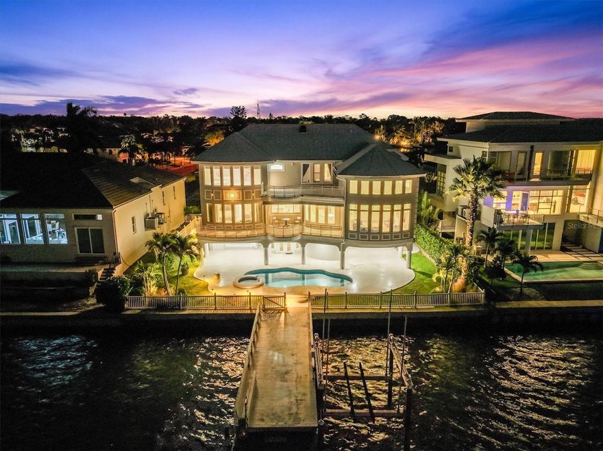 Set against the breathtaking backdrop of the Intracoastal Waterway, this contemporary waterfront estate embodies the essence of Florida’s luxury coastal lifestyle. Thoughtfully designed to capture the beauty of its surroundings, the residence offers a seamless blend of modern architecture, open living spaces, and sweeping views of the water and sky. The open floorplan and five spacious bedrooms provide versatility and comfort, while walls of glass invite natural light and stunning sunset panoramas into almost every corner of the home. The heart of the residence flows effortlessly for entertaining and most comfortable living, with a 3-stop elevator for convenience.  Elegantly and efficiently designed, the kitchen features Subzero and Wolf appliances, and enjoys beautiful water views and abundant natural light.  The luxurious and spacious primary suite is located on the main floor, which is elevated above the floodplain for peace of mind.  Currently serving as on office, bedroom 2 is also located on the main living area.  Additional guest bedrooms are located on the upper floor for privacy, with generous floorplans and outstanding views.  The beautiful pool deck is the perfect spot to enjoy the outdoors, where a private pool, dock, and boat lift create the ultimate setting for relaxation and recreation. Recent upgrades include a new metal roof (2023), impact windows & doors (2019) , and boat lift and composite decking (2020). From your west-facing terrace, evenings unfold in vibrant color as the sun melts into the Gulf. And just moments away, you’ll find the #1 beach in the United States, world-class dining, boutique shopping, nightlife, and easy access to international airports.  This is more than a home — it’s a lifestyle defined by elegance, serenity, and the timeless allure of waterfront living.