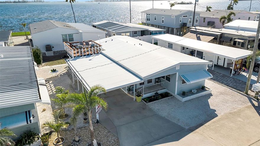 One or more photo(s) has been virtually staged. Experience the quintessential Florida lifestyle in this meticulously maintained residence located in Paradise Bay, a vibrant 55+ "Best Kept Secret" waterfront community. This home shows beautifully and offers the rare privilege of owning one of only four properties in the entire park with a private rooftop deck. From this elevated vantage point, the new owners will enjoy serene bay views and stunning sunsets without the bay front price tag. Paradise Bay is currently undergoing an exciting period of revitalization, making it one of the most desirable locations in the area. The community is seeing the addition of numerous new units, the clubhouse is undergoing a beautiful renovation, and a brand-new dock has just been installed at one of the two boat launches. Residents enjoy a temperature-controlled pool and spa, professional-grade shuffleboard courts, pickleball courts, bocce and a marina with easy access to the Intracoastal Waterway—all just minutes from the pristine beaches of Anna Maria Island. The property itself is in top condition and has been cared for with an incredible eye for detail. Per the seller, only the ground-level lanai received water during recent storms. Following the hurricane, the sellers proactively made significant 2025 improvements to ensure total peace of mind, including a fully updated kitchen with granite countertops, two renovated bathrooms w/granite vanity tops, and brand-new sub-flooring and insulation. The interior has also been refreshed with new carpet and luxury vinyl tile throughout. Please be sure to view the uploaded full list of improvements to see the extensive work done to the framing, plumbing, and mechanicals. Oh and there is a a large storage area to boot! Don't wait—make this unit yours and spend next winter enjoying bay views from your rooftop deck!