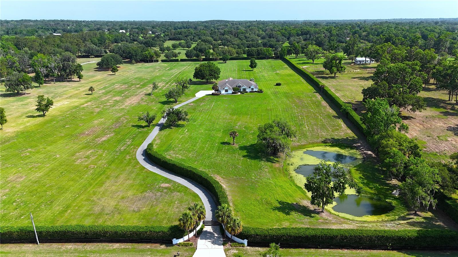 Discover the perfect blend of luxury and tranquility in this stunning property, situated on 25+/- acres of beautifully landscaped grounds. Surrounded by mature privacy hedges on three sides, this serene retreat features a picturesque pond with delightful water features. As you enter the home, you will find a welcoming open floor plan that seamlessly connects the living room, dining space, kitchen and two spacious living & entertaining areas. Flooded with natural light, the living areas create a cozy and inviting ambiance, perfect for relaxation and gatherings. The home also boasts a dedicated home office. This beautifully updated residence includes four spacious bedrooms, each featuring its own private bathroom for ultimate comfort and privacy.
The chic bar area flows gracefully to a gorgeous pool deck, complete with imported stone and a luxurious jacuzzi, making it ideal for unwinding after a hectic day. Additional features include a climate-controlled three-car garage and an advanced smart home system.
Located adjacent to the prestigious Country Club of Ocala, this home epitomizes luxury while offering easy access to various recreational opportunities, including the nearby Santos Trailhead.
Do not miss the chance to make this exquisite property your own; you can also acquire additional acreage. Contact us today for more details or to schedule a private showing!