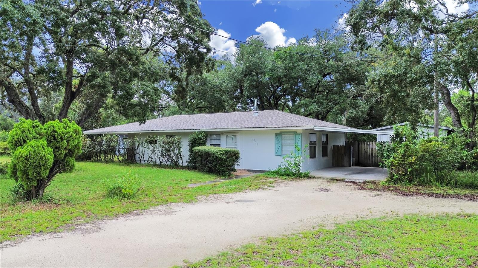 One or more photo(s) has been virtually staged. Welcome to this peaceful Spring Hill neighborhood! This single-family BLOCK home features 2 bedrooms, 1 bathroom, and a bonus room, situated on 0.67 acres with a circular driveway and 1-car carport. This home has a living room and a family room, perfect for family gatherings, making memories. Enjoy an open floor plan with a spacious kitchen, equipped with a gas stove ideal for cooking and entertaining. Enjoy serene privacy under the shade of beautiful trees, with ample space for RV or boat storage. Recent updates include a newer roof (2020) and vinyl flooring.The fenced backyard offers privacy, and a large shed in the back offers extra storage. High and dry, this property requires NO flood insurance as well as NO HOA or CDD. Conveniently located near US 19 and Weeki Wachee Springs, perfect for outdoor enthusiasts who enjoy paddleboarding, kayaking, or visiting Buccaneer Bay Water Park and Pine Island beach