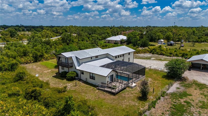 Discover country living at its best in the prestigious, deed-restricted equestrian community of Prairie Creek West. This exceptional 5.37-acre estate offers the perfect blend of rural tranquility and modern convenience, featuring paved roads and dedicated horse trails right at your doorstep. The property is fully fenced for privacy and includes a serene private pond, with the residence tucked away from the road to ensure a peaceful, secluded atmosphere.

The heart of the estate is a one-of-a-kind, custom-built home boasting 4,507 square feet under air and a durable metal roof. Designed with large families in mind, the versatile floor plan offers a minimum of five bedrooms and expansive living spaces. The layout includes a primary suite on the first floor, a ground-floor guest room, and a secondary bedroom suite with a private bath on the second floor alongside additional bedrooms. The main living area makes a grand impression with soaring ceilings, character-rich wood beams, and two-story windows that flood the space with light. A spacious kitchen with wood cabinetry and tile countertops is perfectly positioned for entertaining, situated between the formal dining room and the inviting Great Room.

Outdoor living is elevated by a massive 31'x46' screened-in lanai and an oversized pool, accessible via pocket sliders that seamlessly blend the interior and exterior spaces. It is the ideal setting for BBQing and enjoying expansive country views. Equestrian enthusiasts will appreciate the detached barn with carport, which has been converted into 2 open-air horse stables designed for fresh air and easy access. Completing the home is an oversized two-car garage and a large bonus room located off the main living area, providing ample space for hobbies, a home gym, or a private office.
