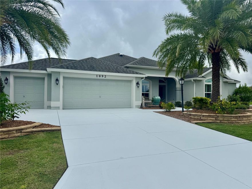 Prepare to be impressed by this absolutely beautiful expanded Gardenia model perfectly situated on a large corner lot in one of The Villages’ most convenient locations. This exceptional home is packed full of upgrades and elegant design touches throughout.The open floor plan is enhanced by the expanded width of the home, making the Living and Dining Rooms feel extra spacious and ideal for entertaining. Engineered French oak flooring flows through the main living areas, while tile adds practicality and style to the wet spaces. The eat-in Kitchen is truly a showstopper, featuring staggered cabinets with crown molding, quartz countertops, stainless steel appliances, a large island with pendant lighting, a breakfast bar, and a cozy nook for casual dining.The Main Bedroom Suite is large and inviting, featuring a tray ceiling, dual closets, and a luxurious en-suite bath with two vanities, abundant storage, a Roman shower, and a private water closet. The front Guest Suite offers its own en-suite bath with shower and a spacious walk-in closet—perfect for visiting family or friends.Down the hall, is the third Bedroom with vaulted ceiling and full Guest Bath. This area is made private by a pocket door and is on the opposite side of the home from the Main Bedroom.The Lanai is glass-enclosed with tile flooring and a dedicated split A/C unit, creating a comfortable year-round retreat. Telescoping sliding doors from the Living Room open fully to this space, offering a seamless indoor-outdoor flow. The Laundry Room is conveniently located off the Kitchen and features cabinetry and a wash sink for added functionality.Additional features include plantation shutters throughout, three solar tubes, transom windows in multiple rooms, and deep crown molding that gives the home a true custom feel. The spacious two-car garage plus golf cart garage provide plenty of parking and storage space.The exterior is just as impressive, with professional landscaping that includes stacked stone borders, lush palms, and a welcoming fountain at the entrance—all creating beautiful curb appeal. This home’s location is ideal, close to shopping, golf courses, recreation, pools, and mailboxes.This meticulously maintained and thoughtfully upgraded home offers elegance, comfort, and convenience all in one. Schedule your private showing today—you’ll be glad you did!