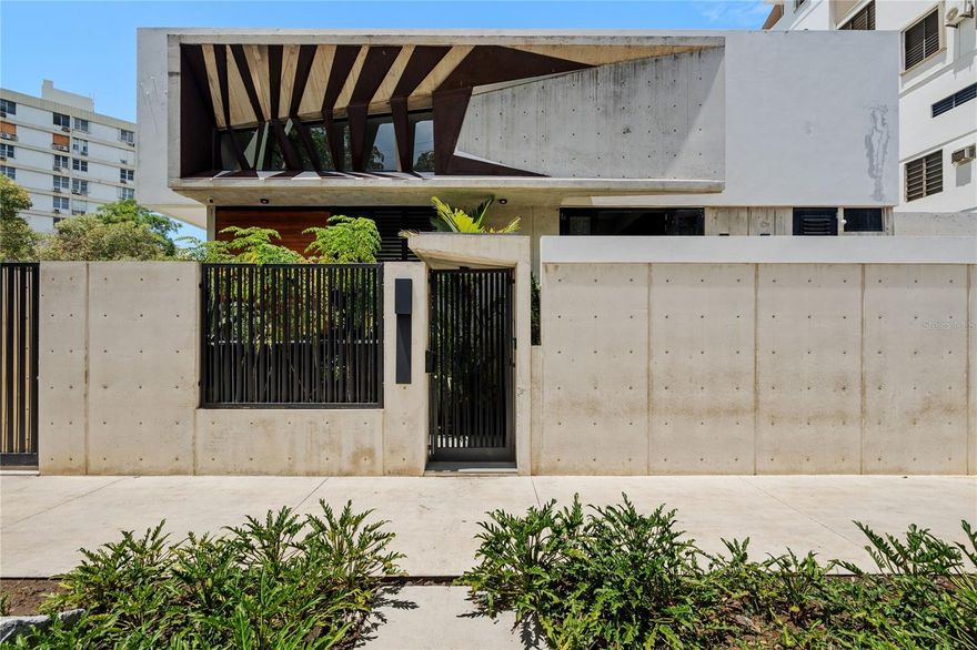 This striking modern residence showcases bold architectural design with clean lines, exposed concrete, and dramatic geometric accents. Behind the private gated entry, lush greenery provides a tranquil contrast to the home’s sleek façade. Large windows invite natural light while maintaining privacy, creating the perfect balance of style and functionality. An ideal choice for those seeking an exclusive urban lifestyle with a touch of sophistication. The open-concept living space features soaring ceilings with a dramatic oversized ceiling fan, polished stone floors, and sleek exposed concrete walls that highlight the home’s architectural character. The gourmet kitchen boasts a minimalist black island and pendant lighting, seamlessly flowing into the dining area with custom wood accents. Expansive glass doors and clerestory windows bathe the space in natural light while connecting the indoors to the lush greenery outside. Elegant finishes, curated artwork, and stylish furniture create a sophisticated yet inviting atmosphere—perfect for both entertaining and everyday living. The property has a full-power generator, 2 emergency water tanks, and garage and carport for 4 cars and a security system for your comfort and peace of mind.
