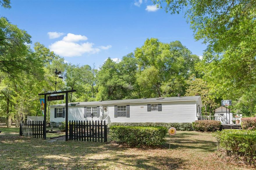 Nearly 7 acres in Gilchrist County with a High Springs address, offering lower property taxes and a peaceful North Florida setting. This 3-bedroom, 2-bath home features two living areas, including a family room with a wood-burning fireplace, along with an eat-in kitchen and separate dining space. Fresh paint and luxury vinyl plank flooring throughout. All bedrooms have walk-in closets, and the split floor plan provides added privacy. The primary suite includes dual vanities and a garden tub. Approximately 3 acres are cleared, with additional wooded acreage for privacy and wildlife. The property includes a small fenced area, two sheds, one with electricity, a two-car carport, a 3-zone irrigation system, and a firepit area—perfect for enjoying evenings outdoors—along with a private well and septic system. Zoned for highly rated Bell schools and conveniently located approximately 3 miles to Poe Springs and Blue Springs, and 6 miles to Ginnie Springs, with easy access to High Springs, Gainesville, and Lake City.