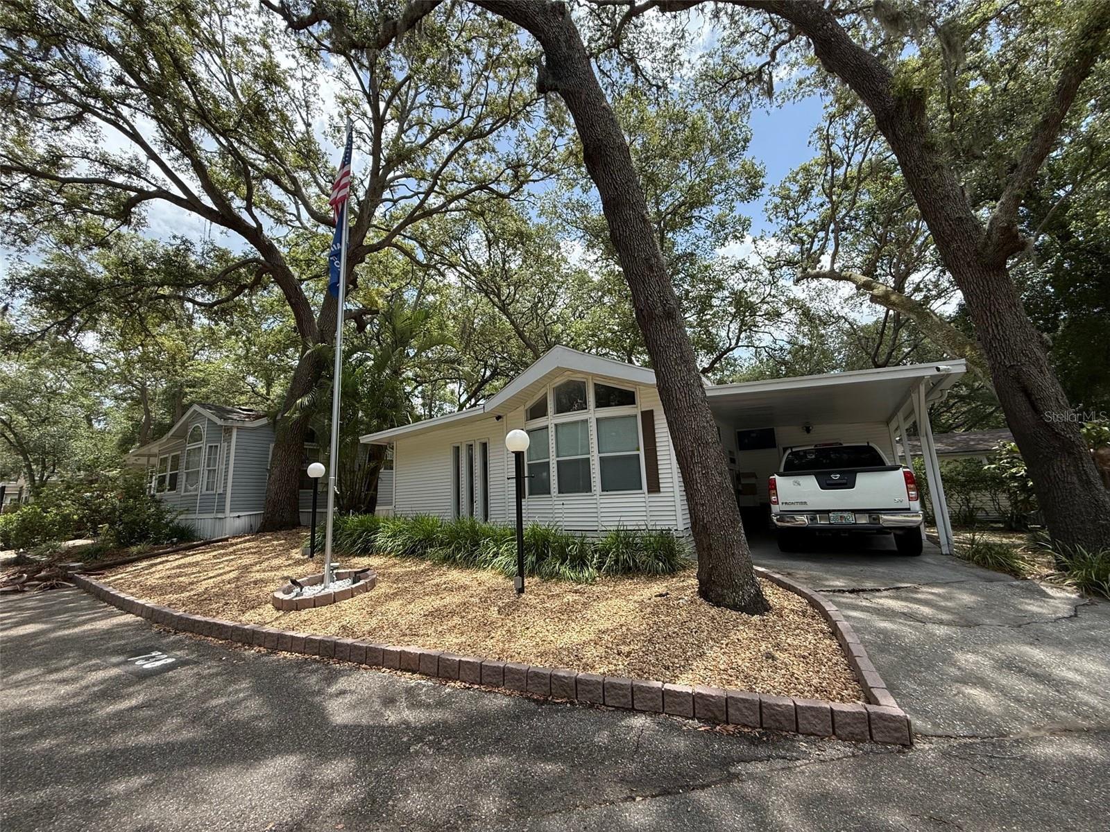 Gated Community where you own the land. This beautiful 2 bedroom 1 1/2 bath features new flooring in park model, Updated kitchen and fixtures, enclosed Florida room under air. Large corner lot with one car carport, attached utility room, paved parking, open patio area to get some fresh air. Exterior front has been rock and landscape stones and is complete with a flagpole. Inside you will find lots of cabinet space throughout, huge eat-in kitchen area with 2 large pantries and breakfast bar, even a dishwasher. Fireplace, stackable washer/dryer inside, large shower with handicap accessibility. The monthly Condo fees include water, sewer, trash pickup, 24/7 virtual gatehouse, 110,000-gallon Pool, On-Site Condo Office and Management, and maintenance of community grounds. Pay your HOA dues and metered electric bill for a prime location in sunny Florida! Our location is very convenient with lots of dining, hospital and shopping close by. You own the land, No lot rent.
