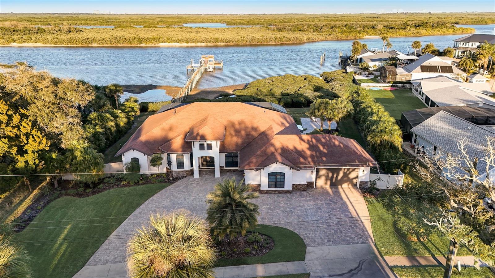 This exceptional waterfront property nestled in a private cove boasts over 1/2 acre and over 175 ft on the main channel of the prime direct Intracoastal waterway. This is the epitome of the quintessential Florida lifestyle. Whether you seek a vacation residence, retirement haven, secondary home, permanent dwelling, or investment property, look no further – your dream is on the verge of becoming a reality.
Approaching this exquisite abode, you'll immediately notice the elegantly sealed paver driveway and meticulously landscaped surroundings. The oversized climate controlled 3-car garage with epoxy floor finish, impact windows, and freshly painted exterior complete the picture of perfection. Upon entering through the front door, prepare to be enchanted. The unobstructed panoramic view of the Intracoastal waterway spans right from your own backyard. The sheer beauty of this sight is truly awe-inspiring, transforming this property into a breathtaking masterpiece that you can call home.
The interior showcases gorgeous teak flooring throughout most of the main living area, while the kitchen boasts lovely tile to encapsulate its charm. The grand living room is a haven of luxury, offering unbelievable river views. A stunning coffered ceiling adds to the opulence, while hurricane-rated sliding doors open fully and pocket into the walls, seamlessly merging the outdoors with the interior living space. Feel like a part of the party as you create culinary masterpieces in the "gathering room" (also known as the kitchen). Whether you choose to gather around the granite countertop, enjoy a meal in the breakfast nook, or dine formally in the dining room sipping water fresh from your very own whole house water purification system, there is ample space for everyone. Stainless steel appliances, including a gas range, abundant granite countertops, an extensive pantry, and ample cabinetry to accommodate even the most extensive collection of cookware, make this kitchen a chef's paradise.
The generous-sized bedrooms offer comfort and functionality, while the mother-in-law suite affords breathtaking river views. The captains quarters not only provide easy access to the pool area but also feature a walk-in closet that doubles as a safe room. There is a whole house generator. Step outside onto the expansive screened in 2,600 sq ft patio and pool area. Relax in the 18x30 self-cleaning pool, luxuriate in the hot tub, or unwind on the couch while enjoying your favorite movie and the warmth of the gas fireplace. Not only are there two covered seating areas, but there is also a full summer kitchen complete with a gas hook up. Beyond the screened enclosure, you'll discover a 550 sq ft paverd courtyard, cared for garden and 12x12 greenhouse with electric and water. Immerse yourself in the beauty of the surroundings as you take a leisurely stroll down the 280 ft long dock, featuring two levels, a floating dock, a fish cleaning station, and amenities such as electric, water, 13,000 lb boat lift, and seating areas. Can you imagine watching a space launch from the comfort of your pool? It's an experience like no other!
Make this extraordinary property your new home.