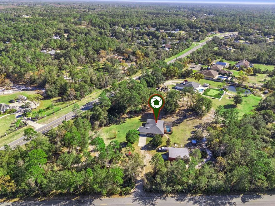 One or more photo(s) has been virtually staged. Set on a secluded, high and dry 2.62-acre corner lot with NO HOA, this 3-bedroom, 2-bath home offers exceptional privacy, space, and versatility. Tucked away and only visible from the driveway, the property provides a truly private setting—perfect for those seeking peace and room to spread out. Whether you need space for toys, hobbies, or future expansion, this property delivers in a big way. The standout feature is the two-garage setup: a 2-car attached garage plus an impressive 1,200-square-foot detached garage/workshop. Designed for serious functionality, the detached garage includes a 11,000-lb car lift (car lift can be removed upon request), two roll-up garage doors, and a large 12' x 12' entrance, making it ideal for car enthusiasts, contractors, storage, or anyone needing substantial workspace. The expansive acreage offers endless possibilities for outdoor living, RV or boat parking, or simply enjoying the privacy of your own land. Major upgrades provide peace of mind, including a new roof (2024), AC (2020), water heater (2025), and recently pumped septic tank (2025). Inside, the home features a thoughtfully designed layout with a separate living room, family room, dining room, and breakfast nook—providing flexibility for everyday living and entertaining. The kitchen is well-appointed with granite countertops, stainless steel appliances, and ample storage. The primary suite is a true retreat with tray ceilings, dual closets, dual vanities, a soaking tub, and a walk-in shower. Step outside and enjoy Florida living year-round in the screened-in pool, perfect for relaxing or hosting guests. Centrally located with convenient access to I-4, shopping, dining, Daytona beaches, and Orlando attractions, this property combines privacy, functionality, and convenience—a rare opportunity on a truly private, oversized lot. Schedule your private showing today!