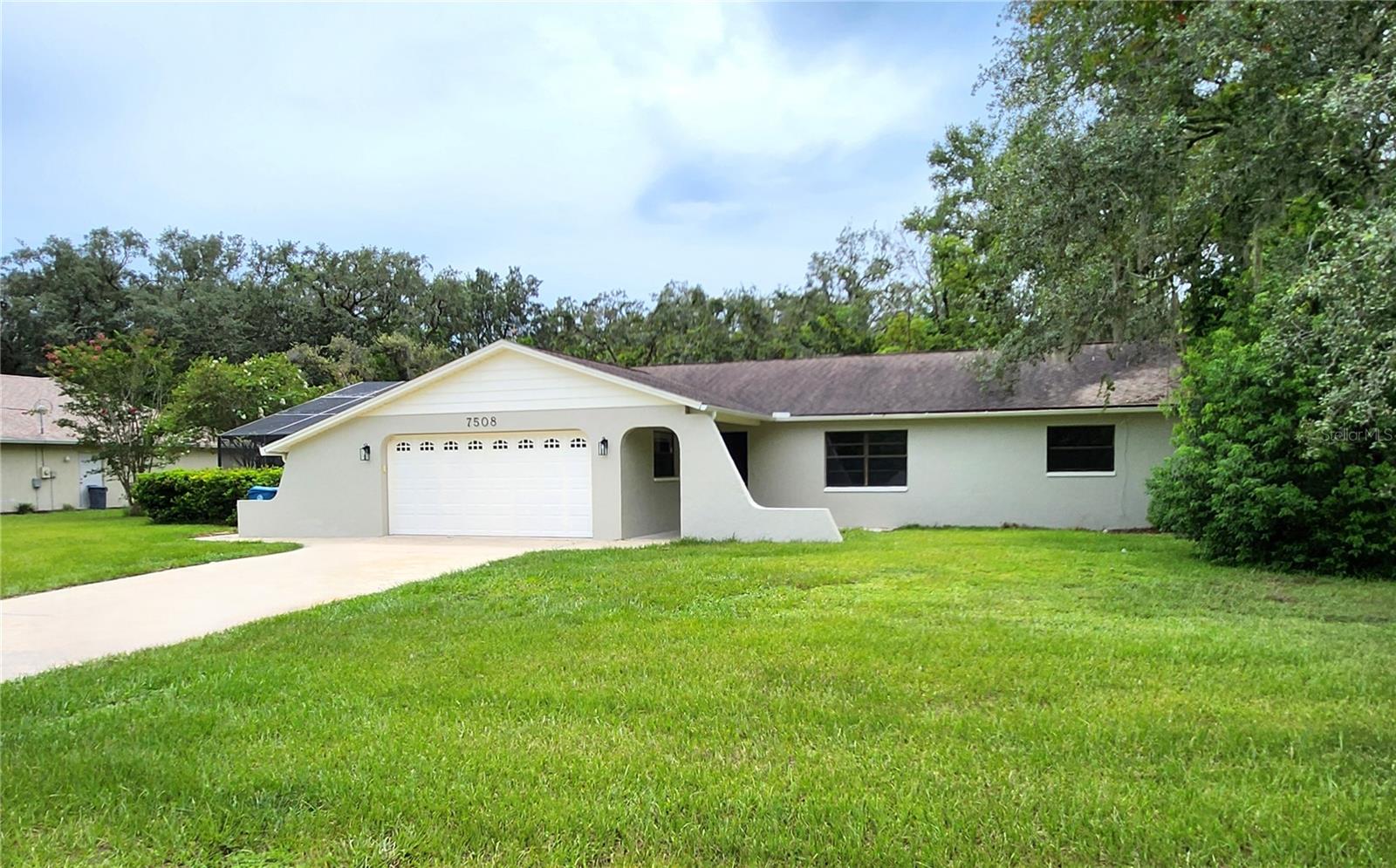Newly Renovated Pool Home on Corner Lot in Spring Hill! Welcome to this beautifully updated 3 bedroom, 2 bath pool home situated on a spacious ¼-acre corner lot. Freshly painted inside and out, the home features brand-new flooring throughout for a modern, move-in ready feel. Step inside to the formal living room and continue into the all-new kitchen, complete with new cabinetry, granite countertops, stainless steel appliances, and a large breakfast bar that opens to the family room. The adjoining dining area is perfect for gatherings, while the cozy family room offers a fireplace and French doors leading to the lanai and pool area. The split floor plan provides privacy, with a master suite featuring a walk-in closet and a fully remodeled bath with a granite-topped vanity, makeup area, new tile flooring, and walk-in shower. Two oversized secondary bedrooms share a renovated hall bath with a granite vanity and a tub/shower combo. Enjoy outdoor living in the expansive covered lanai overlooking the deep, screened-in pool, ideal for relaxing or entertaining. The 2-car garage includes an extended area with a large workbench, perfect for storage or a workshop. Best of all—NO HOA, NO CDD, and lower utility costs thanks to the septic system. This home checks all the boxes—schedule your private tour today!