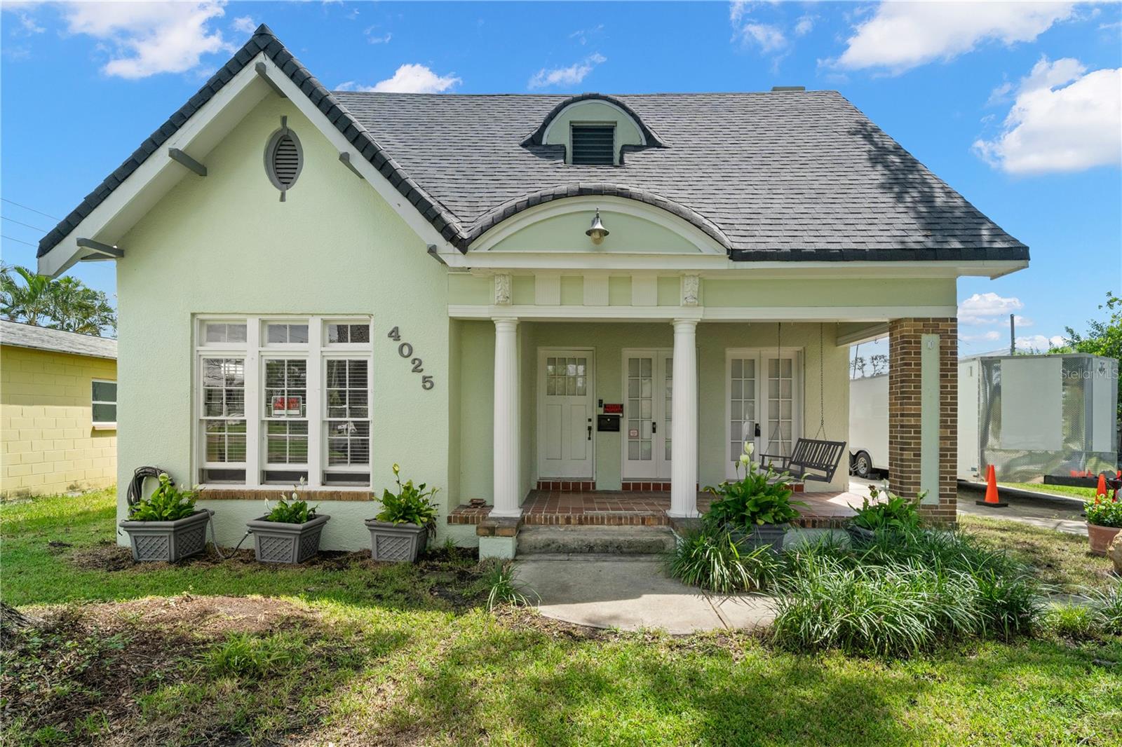 Step into a slice of history with this charming nearly 100-year-old Tutor Revival style home in the desirable Shore Acres neighborhood. Boasting timeless character and classic features, this 3-bedroom, 1-bathroom residence offers a perfect blend of vintage appeal and endless POTENTIAL for modern updates. UNLOCK even more potential with wood stairs leading to an approximately 880 sq ft ATTIC SPACE. Bring your imagination and VISION to RECONFIGURE this area and significantly INCREASE the heated square footage. Envision your dream TWO-STORY home, possibly with vaulted ceilings on the 2nd floor. Exterior highlights include a welcoming covered FRONT PORCH with tile floors, tongue-and-groove ceilings, and elegant columns. A side porch adds additional outdoor space, while the EXPANSIVE DRIVEWAY provides convenient OFF-STREET parking. The property is enclosed by a vinyl and wood PRIVACY FENCE, with mature oak trees enhancing the curb appeal. Enjoy outdoor living on the wood deck and take advantage of the parking pad in the backyard ideal for BOAT or RV STORAGE. Enjoy peace of mind with a NEWER shingle ROOF replaced in ~2023. Inside, double French doors open to a spacious living room featuring WOOD FLOORS, a wood-burning FIREPLACE, crown molding, BUILT-IN shelving, ceiling fans, and solid wood doors. Wood floors extend throughout much of the home, with tile in wet areas. The spacious FORMAL DINING room is perfect for entertaining. A UTILITY ROOM on the back porch houses the washer and dryer connections. The bathroom showcases hexagon tile floors, a single vanity, and a tub/shower combo. PERIOD-INSPIRED WOODEN windows add to the charm. This property flooded during Hurricane Helene, and the City of St. Pete provided a letter available upon request stating the structure "was NOT found to be substantially damaged." This gem is ready for your personal touch to make it shine again.