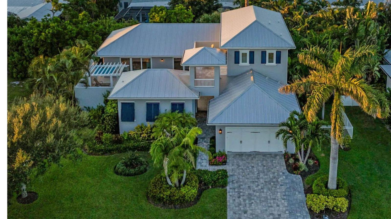 Exuding coastal charm, this spacious four bedroom, three full baths, and two half baths Brista Homes masterpiece is a true tropical find just 500 feet from the beach. Behind its inviting façade lies a private courtyard oasis with a resort-style heated pool, sun shelf, and pergola with rain-shower waterfall—an everyday escape that feels like vacation. The first-floor master has an en suite bath with marble countertops, dual sinks, doorless shower and a soaker tub. Rich details such as wainscoting, shiplap accents, wide plank oak floors, beamed tray ceilings, crown moldings, and 12” baseboards create a timeless backdrop. Modern comforts abound with plantation shutters, Lutron lighting and shades, impact windows and doors, a security system, metal roof, and three zone AC. The kitchen boasts a large island, Sub Zero refrigerator, Thermador appliances and an adjoining butler’s pantry. A private office and generous living spaces add convenience. Guests will love the second-floor guest rooms and terrace overlooking the courtyard or the separate casita, complete with a bedroom, full en suite bath, and closet. A beach access point is just steps away. Ideally positioned mid-key, the location offers easy access to both north and south Longboat amenities—all with the added benefit of no HOA fees. The gated yard makes it ideal for pets, and the home is offered move-in ready, with designer furnishings available separately. This property embodies the effortless elegance of Longboat Key living.