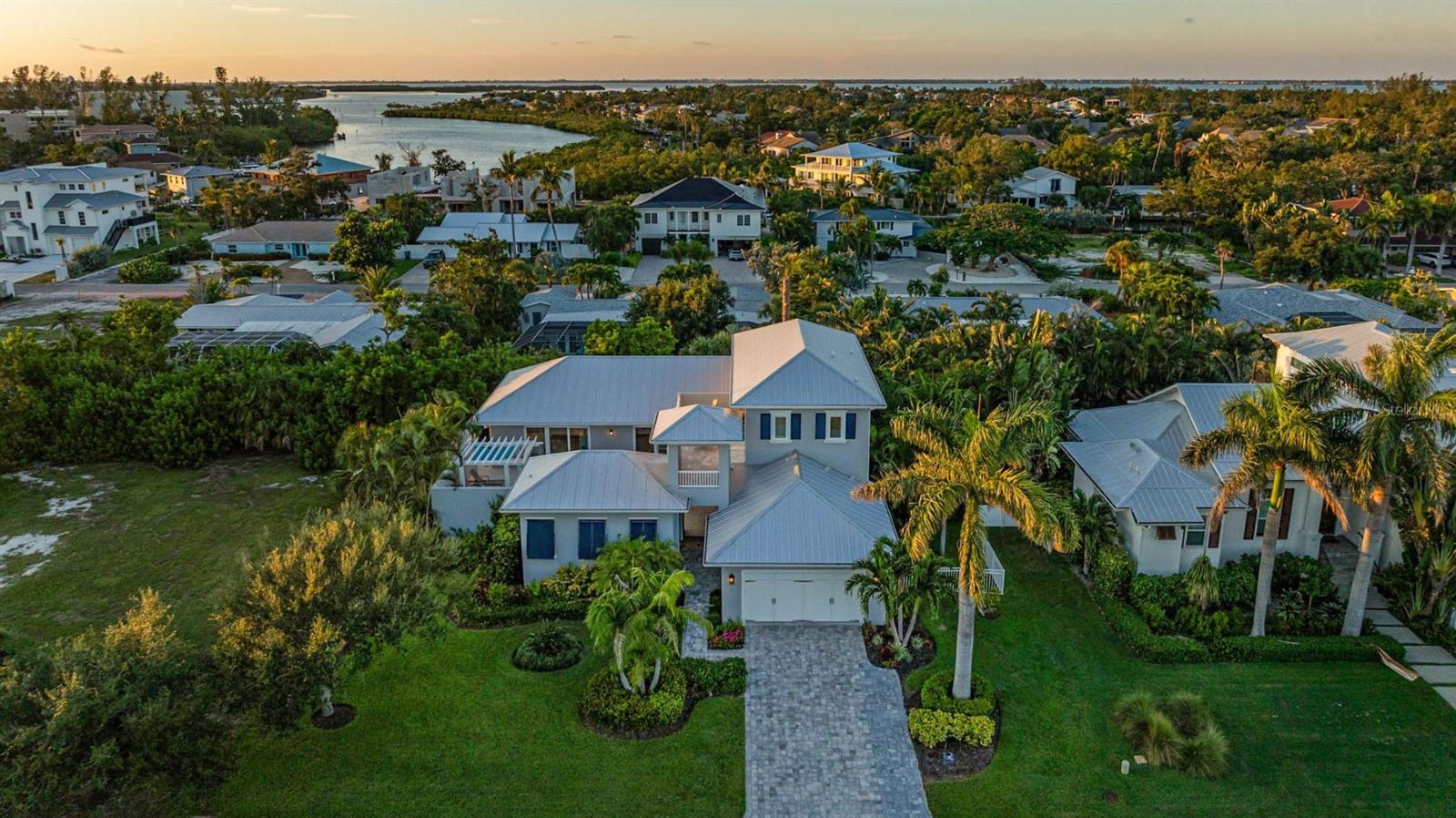 Exuding coastal charm, this spacious four bedroom, three full baths, and two half baths Brista Homes masterpiece is a true tropical find just 500 feet from the beach. Behind its inviting façade lies a private courtyard oasis with a resort-style heated pool, sun shelf, and pergola with rain-shower waterfall—an everyday escape that feels like vacation. The first-floor master has an en suite bath with marble countertops, dual sinks, doorless shower and a soaker tub. Rich details such as wainscoting, shiplap accents, wide plank oak floors, beamed tray ceilings, crown moldings, and 12” baseboards create a timeless backdrop. Modern comforts abound with plantation shutters, Lutron lighting and shades, impact windows and doors, a security system, metal roof, and three zone AC. The kitchen boasts a large island, Sub Zero refrigerator, Thermador appliances and an adjoining butler’s pantry. A private office and generous living spaces add convenience. Guests will love the second-floor guest rooms and terrace overlooking the courtyard or the separate casita, complete with a bedroom, full en suite bath, and closet. A beach access point is just steps away. Ideally positioned mid-key, the location offers easy access to both north and south Longboat amenities—all with the added benefit of no HOA fees. The gated yard makes it ideal for pets, and the home is offered move-in ready, with designer furnishings available separately. This property embodies the effortless elegance of Longboat Key living.