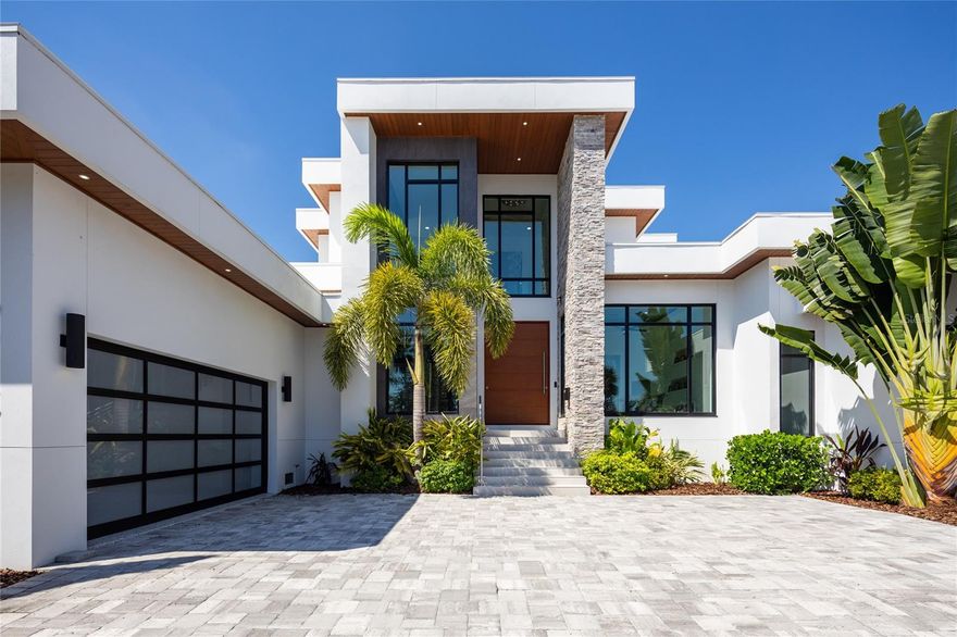 Introducing a Contemporary Waterfront Masterpiece in Tampa Bay. Striking modern architecture and clean, minimalist design come together in this extraordinary custom-built waterfront residence. Completed in 2023, this home makes a bold statement with its commanding curb appeal, soaring 28-foot entry, and dramatic 23-foot foyer. Brilliant natural light, soaring ceilings, and meticulous craftsmanship set the stage for a refined coastal lifestyle.
The open-concept floor plan highlights a chef’s dream kitchen with custom cabinetry, pearl-white quartz island, Thermador appliances, gas cooking, full-height wine chiller, and built-in espresso machine, complemented by a discreet butler’s pantry. Expansive living and dining areas open seamlessly to the water, while the executive-style office and designer guest bath add both elegance and function.
The owner’s suite is a private sanctuary with breathtaking views, balcony access, dual walk-in closets, and a spa-inspired bath featuring custom vanities, a Jacuzzi soaking tub, and a glass-enclosed multi-head rain shower. Upstairs, two additional en suite bedrooms and a large media room extend to a 330-square-foot covered terrace with commanding views of the bay.
Outdoor living is elevated with over 1,200 square feet of covered waterfront terraces, a resort-style pool and spa, outdoor kitchen, and lush landscaping. Waterfront amenities include an updated seawall, large composite dock, kayak/paddleboard launch, boat lift, and mooring capacity for a sizable yacht.
Located just ten minutes from downtown St. Petersburg and six minutes from the Gulf beaches, this residence offers an extraordinary blend of serenity and convenience. Nestled within the highly coveted, gated enclave of Bayway Isles, the community is distinguished by its 24/7 guarded security, pristine surroundings, and enduring sense of privacy.
This estate is not simply a residence but a testament to vision, artistry, and uncompromising craftsmanship. More than a home—it’s a statement of modern luxury and life without compromise. Arrange your private showing today and experience the pinnacle of waterfront living.
